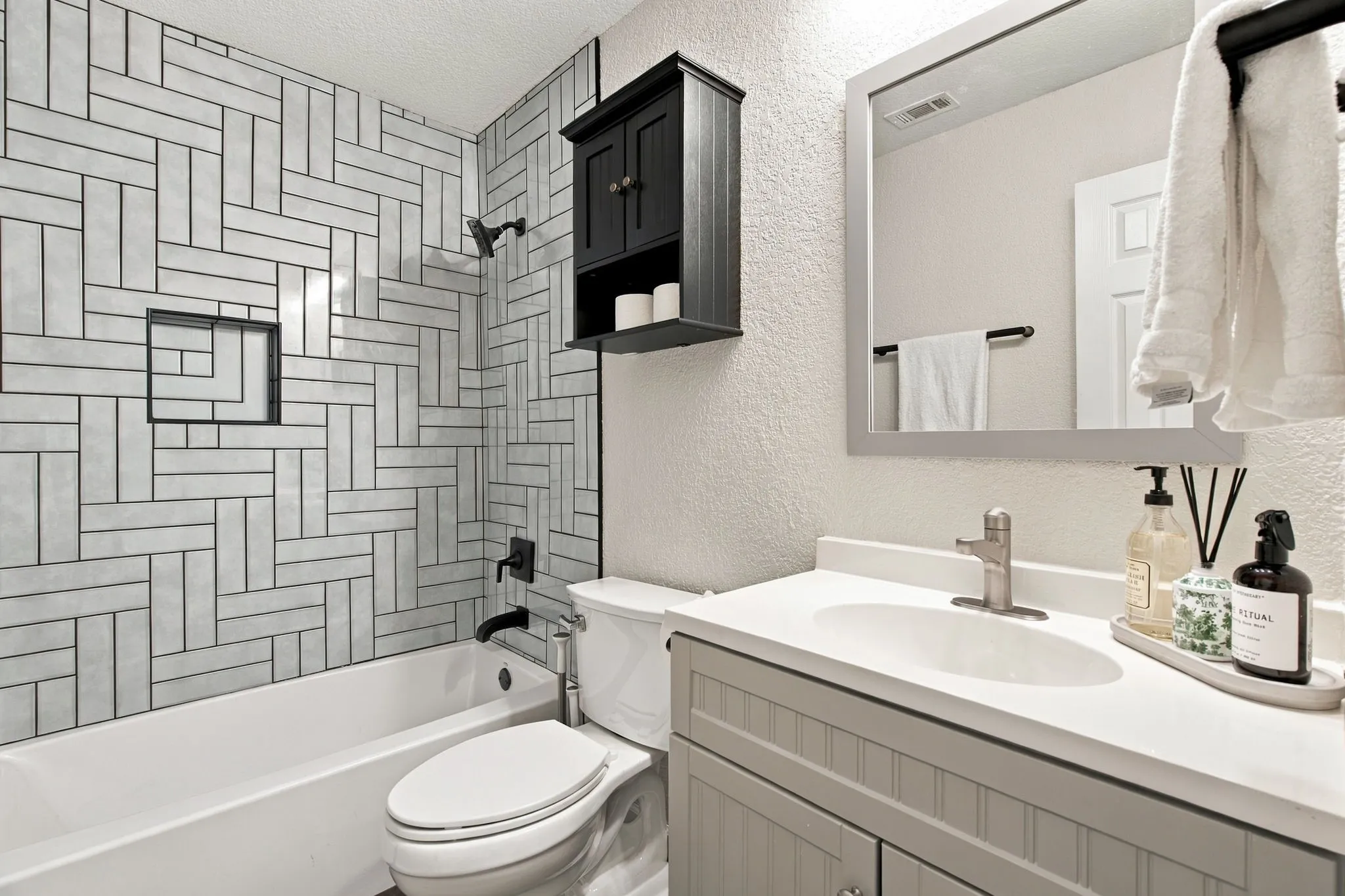 Subway tile shower surround with a herringbone pattern, integrated shower niche, and matte black fixtures