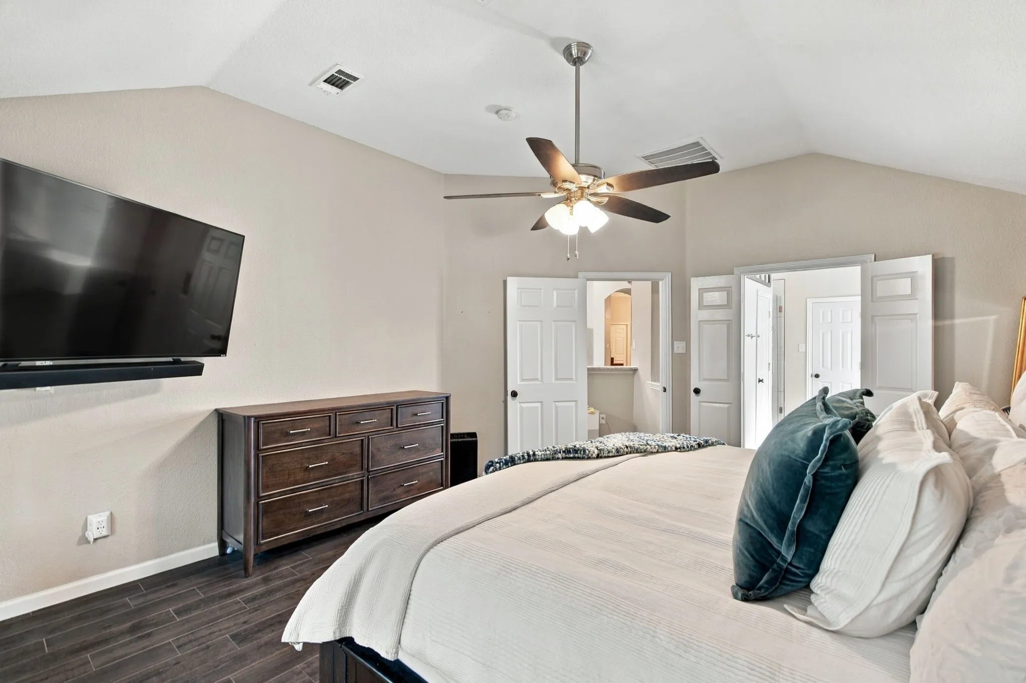 Vaulted ceilings, wood-finish flooring, ceiling fan, and white paneled doors