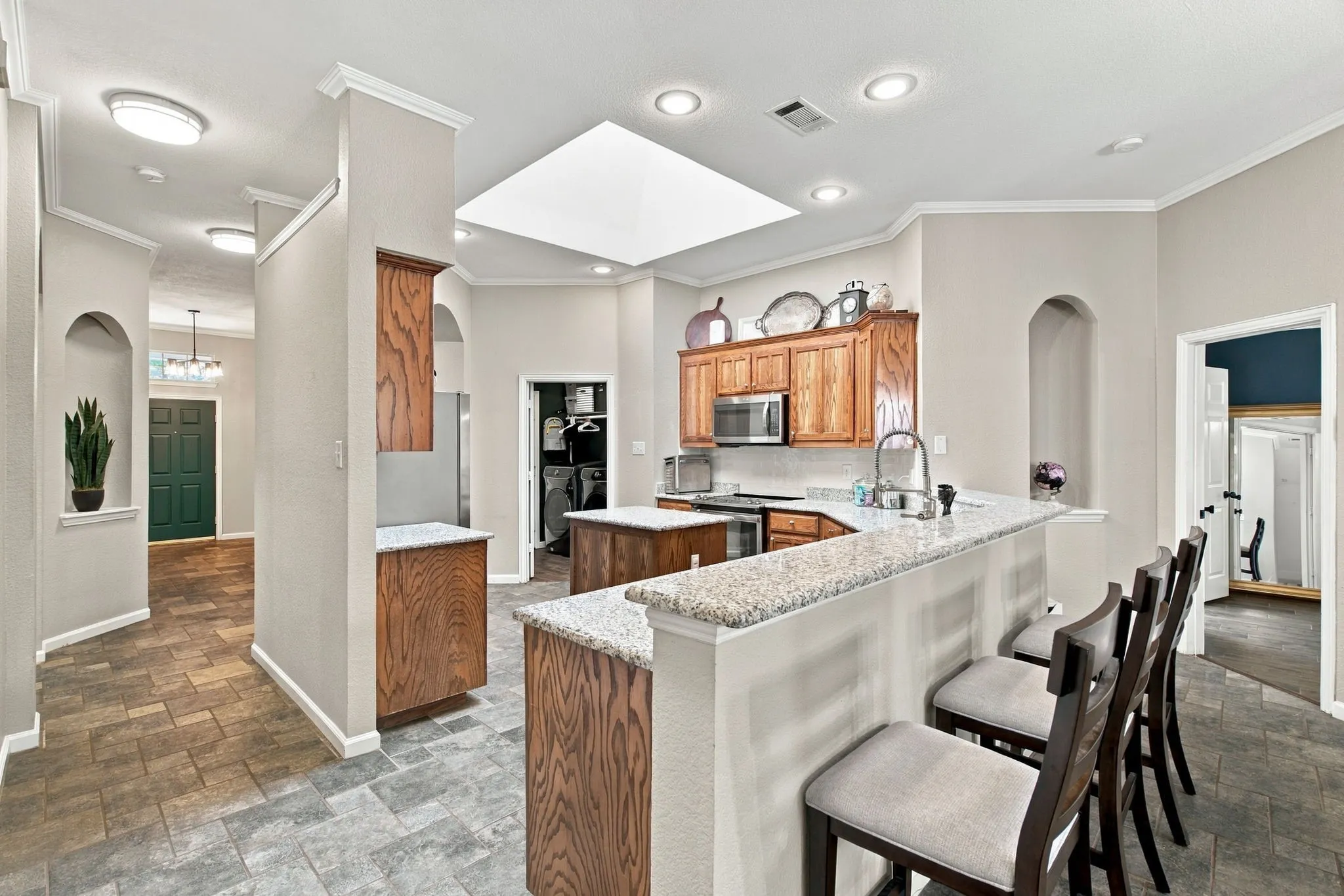 Kitchen featuring wood-finish cabinetry, granite countertops, stainless steel appliances, and an island with bar seating