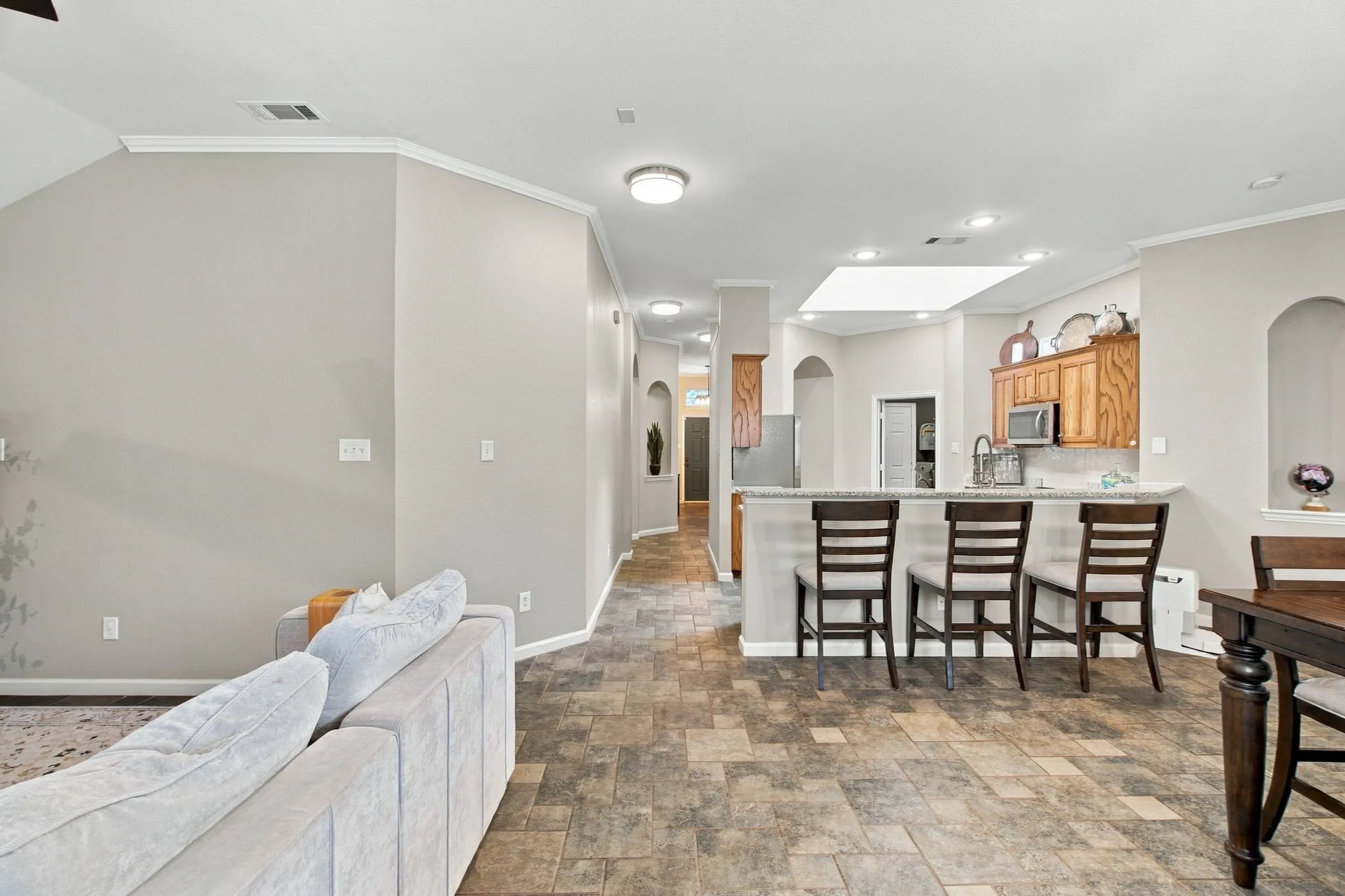 Kitchen bar seating with granite-style countertop, recessed lighting, and wood-finish cabinetry