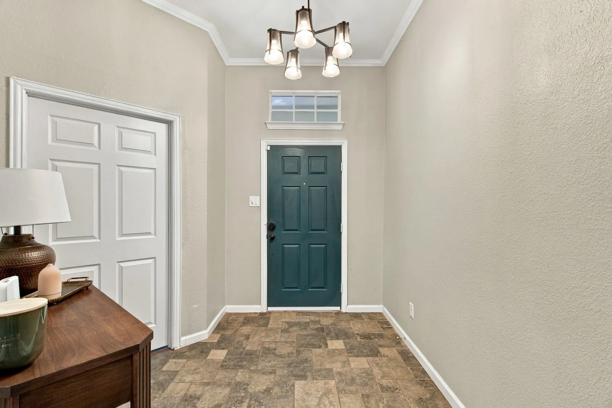 Vaulted ceiling with crown molding and a multi-light chandelier