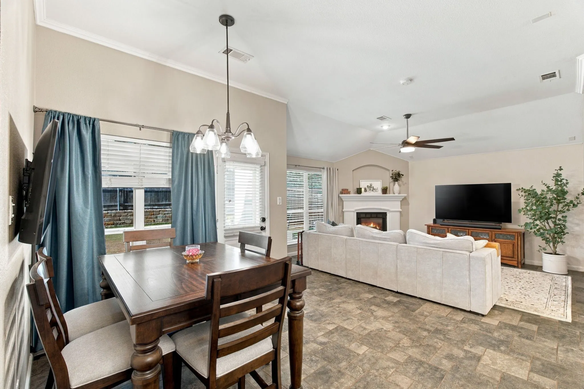 Vaulted ceiling with a ceiling fan, fireplace with mantel, window with blinds, and wood-finish flooring
