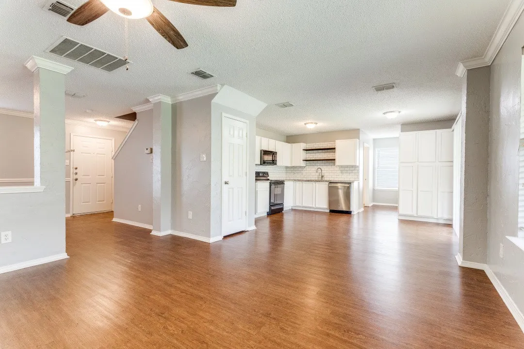 Unfurnished living room with a textured ceiling, dark wood-style floors, ceiling fan, and crown molding