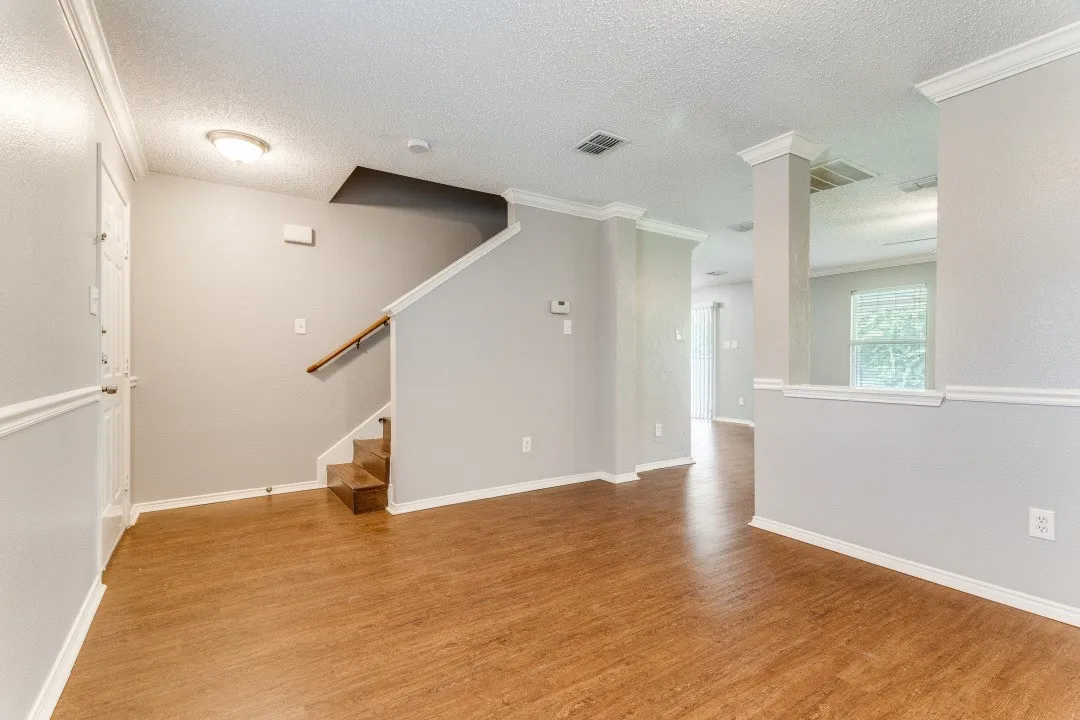 Unfurnished room with a textured ceiling, light wood-style floors, stairway, and crown molding