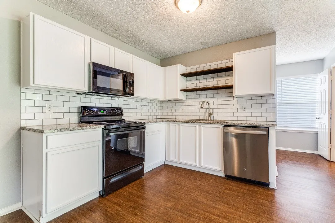 Kitchen featuring open shelves, black appliances, light stone countertops, white cabinetry, and a textured ceiling