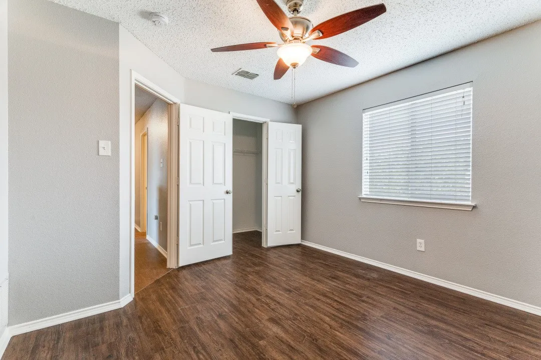 Unfurnished bedroom with dark wood-type flooring, a textured wall, a ceiling fan, and a textured ceiling