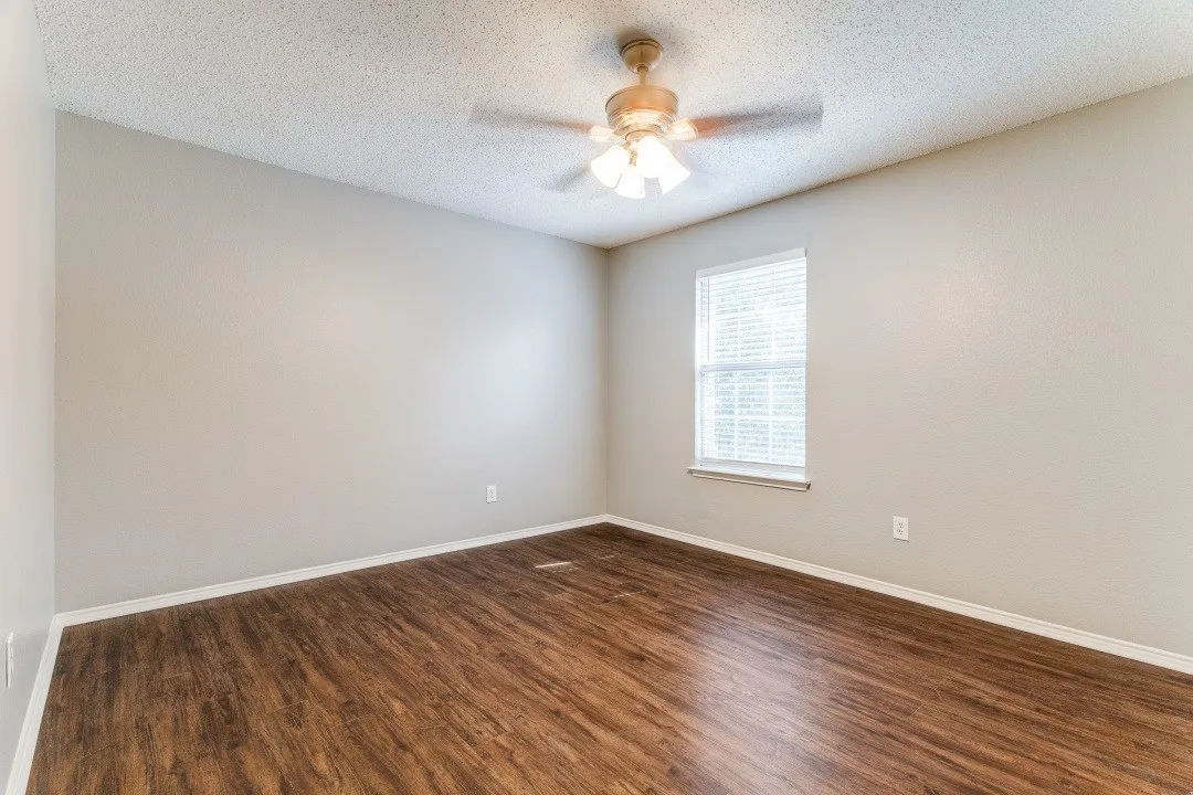 Spare room featuring dark wood-style floors, a textured ceiling, and a ceiling fan