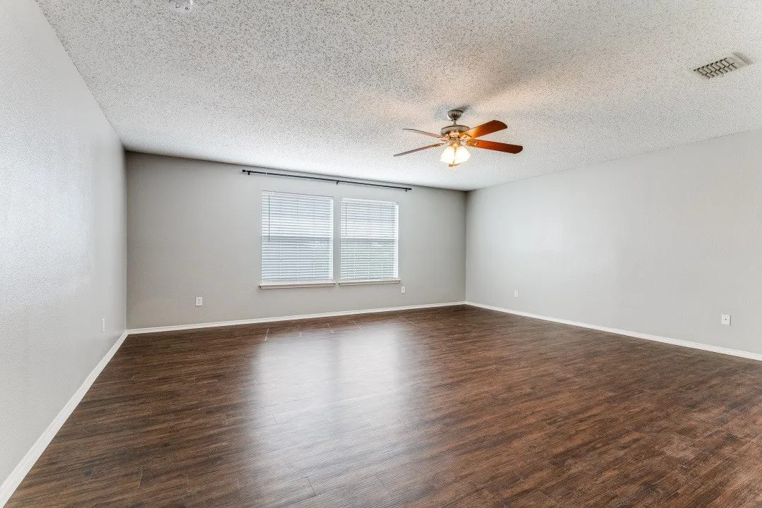 Spare room featuring dark wood-type flooring, a textured ceiling, and a ceiling fan