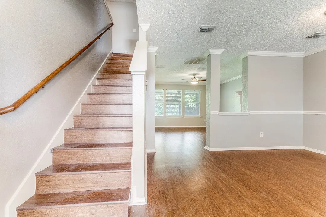 Staircase with a textured ceiling, wood finished floors, and ornamental molding