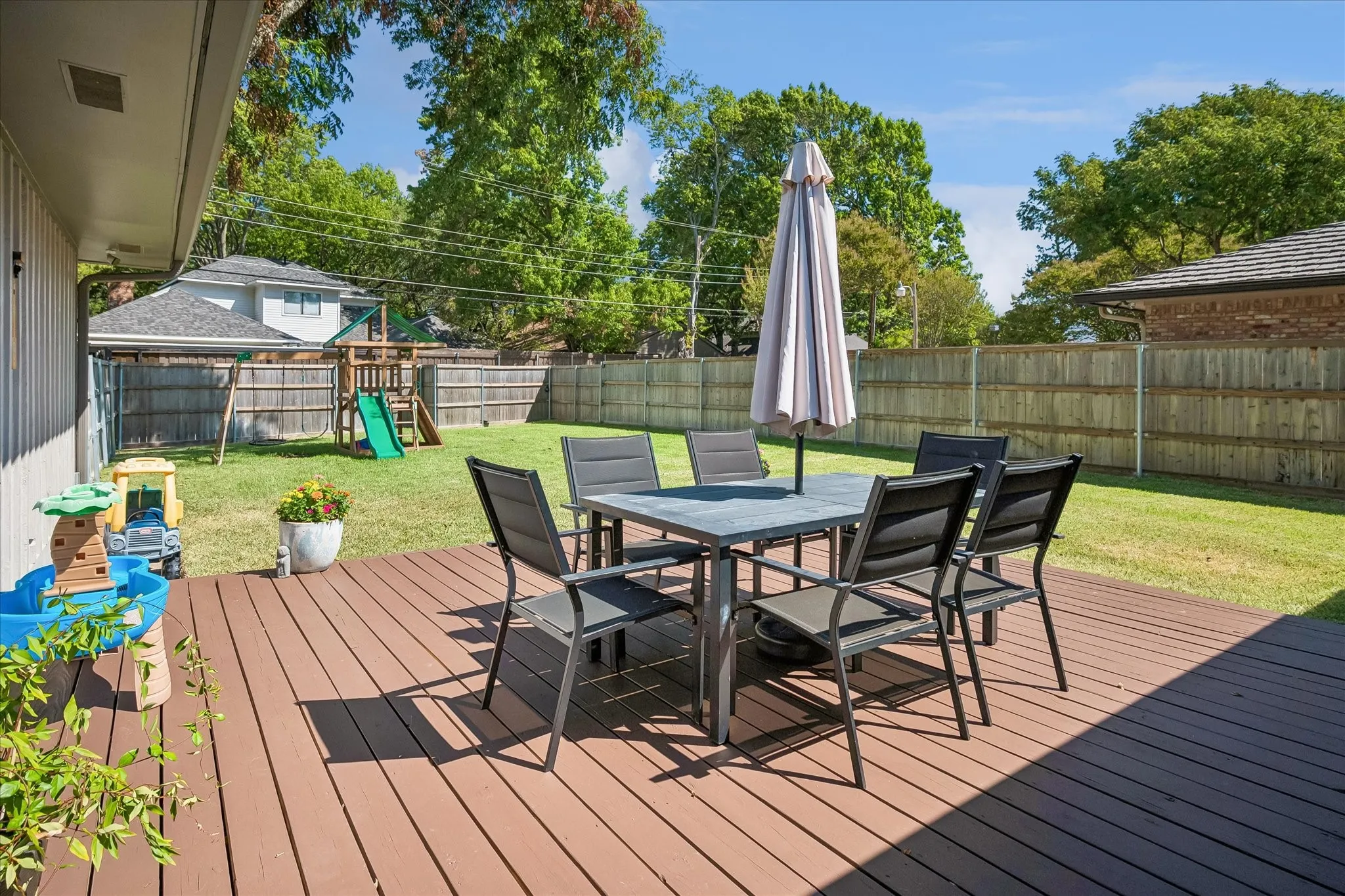 Expansive wood-finish deck with a manicured lawn and privacy fencing