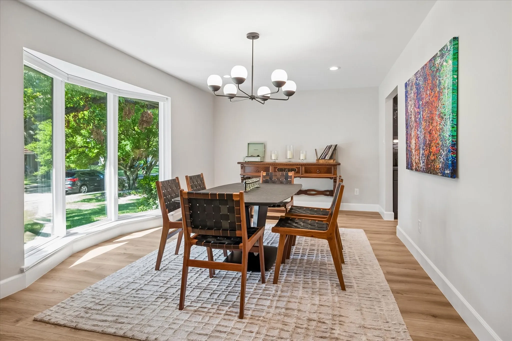 Bay window with multiple panes, wood-finish flooring, recessed lighting, and a contemporary multi-bulb chandelier