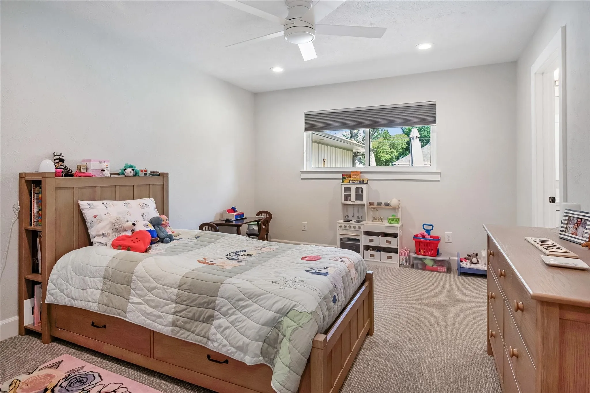 Recessed lighting, ceiling fan, window with roller shade, neutral wall paint, and carpeted flooring