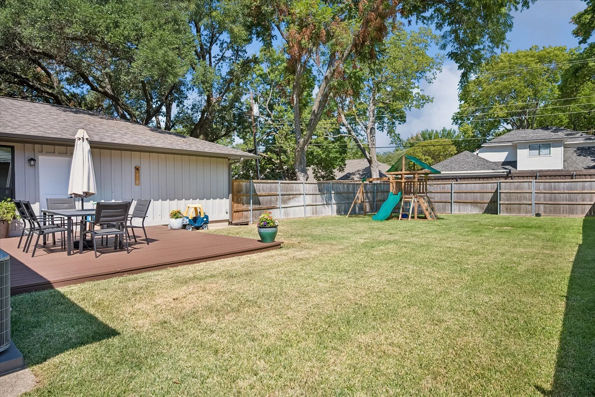 Expansive backyard with a composite deck, privacy fencing, and mature trees