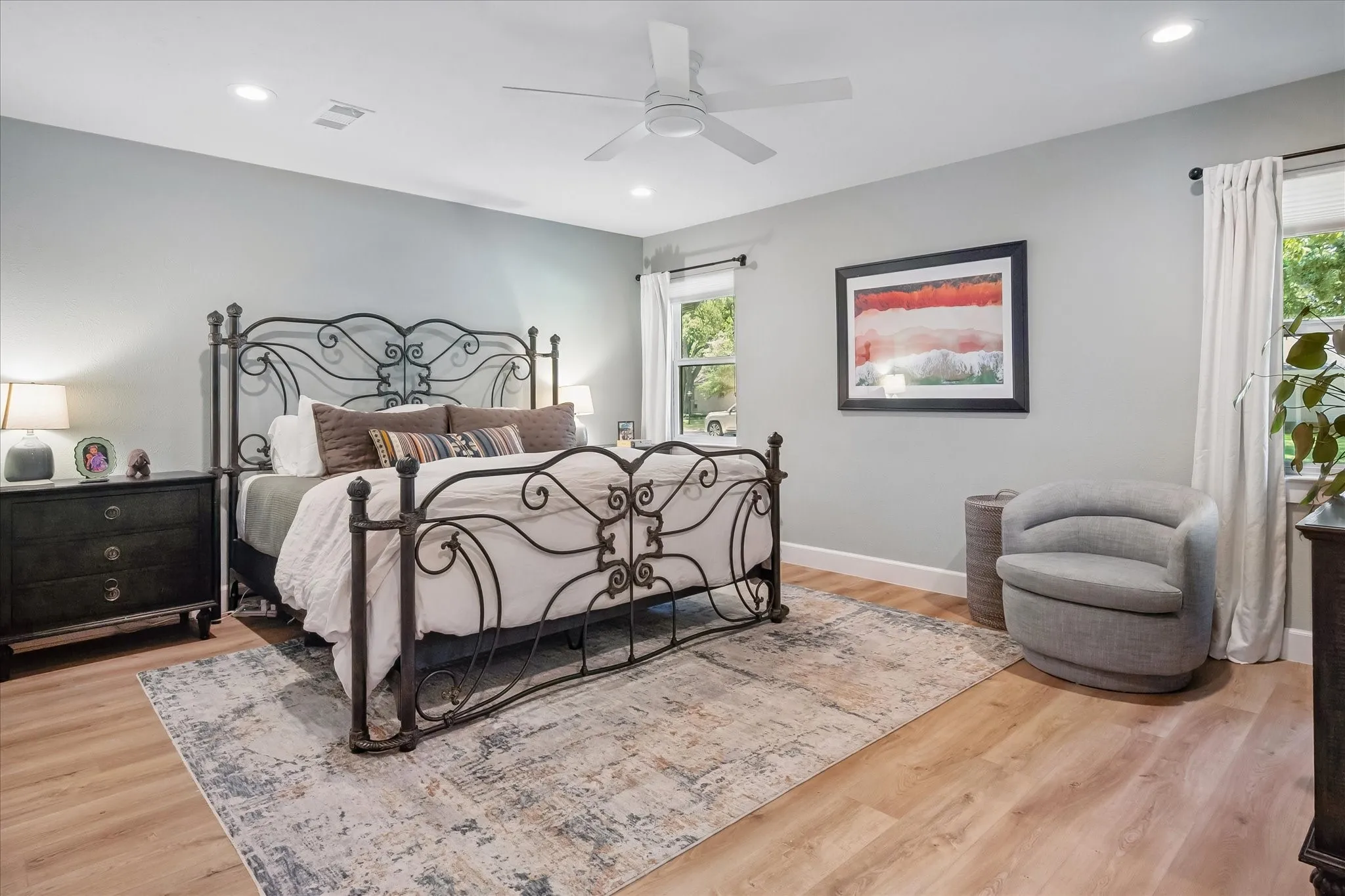 Recessed lighting, wood-finish flooring, ceiling fan, and multiple windows with curtain rods