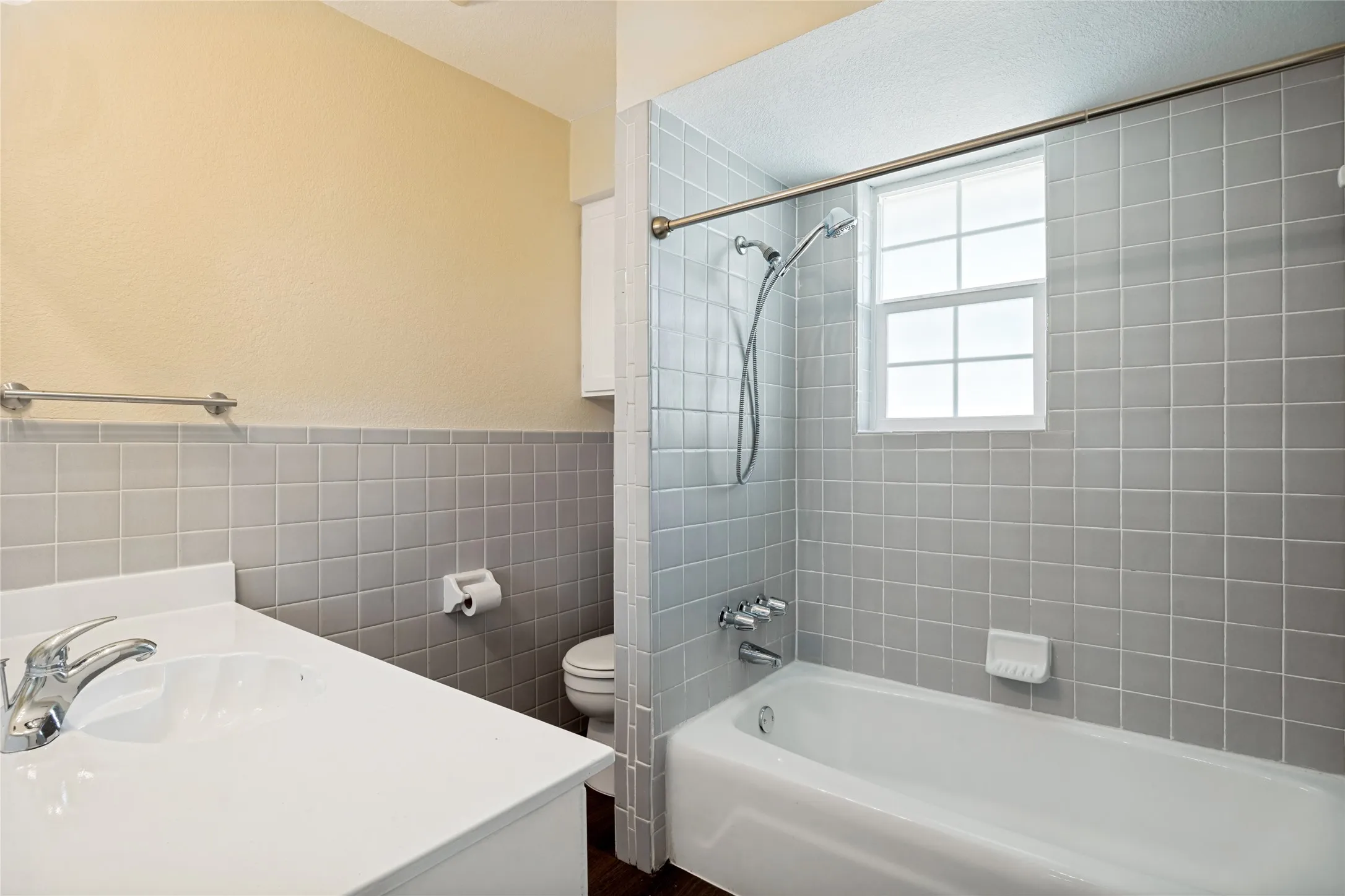 Bathroom featuring a single vanity, tiled shower-tub combination, and a window for natural light