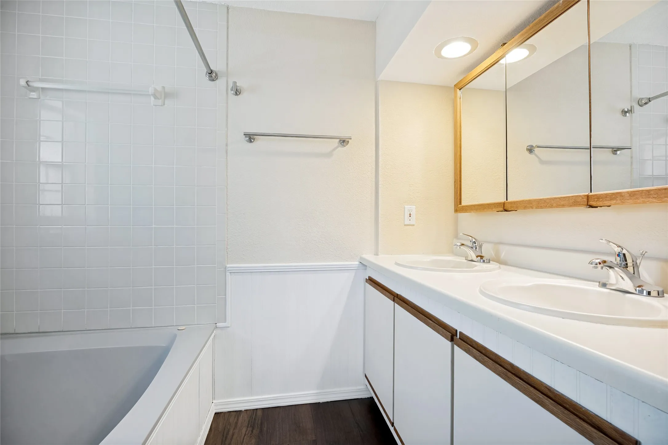 Dual basin vanity with white cabinetry and wood-finish pulls