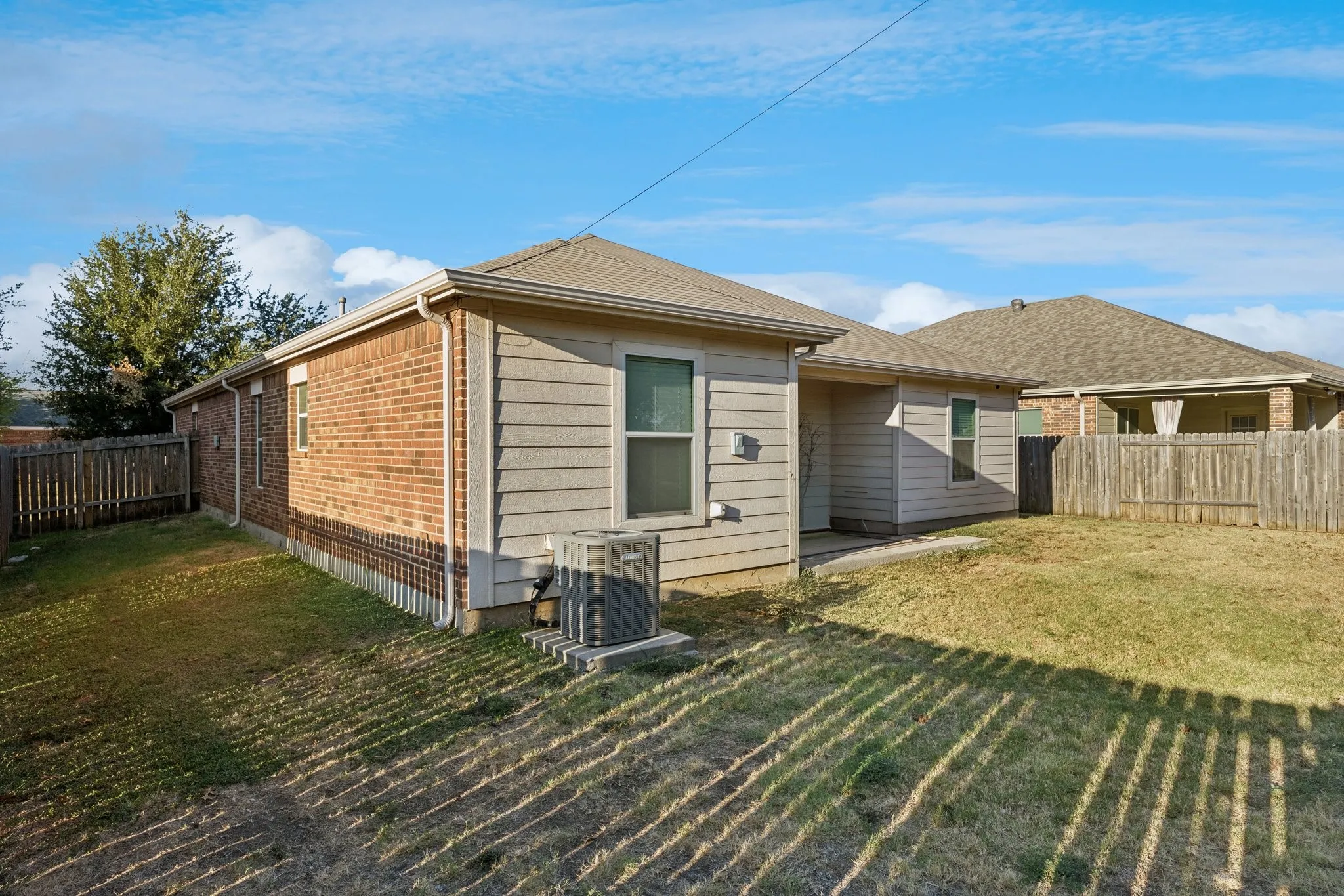 Rear exterior with a wood fence, brick siding, horizontal siding, and an outdoor HVAC unit