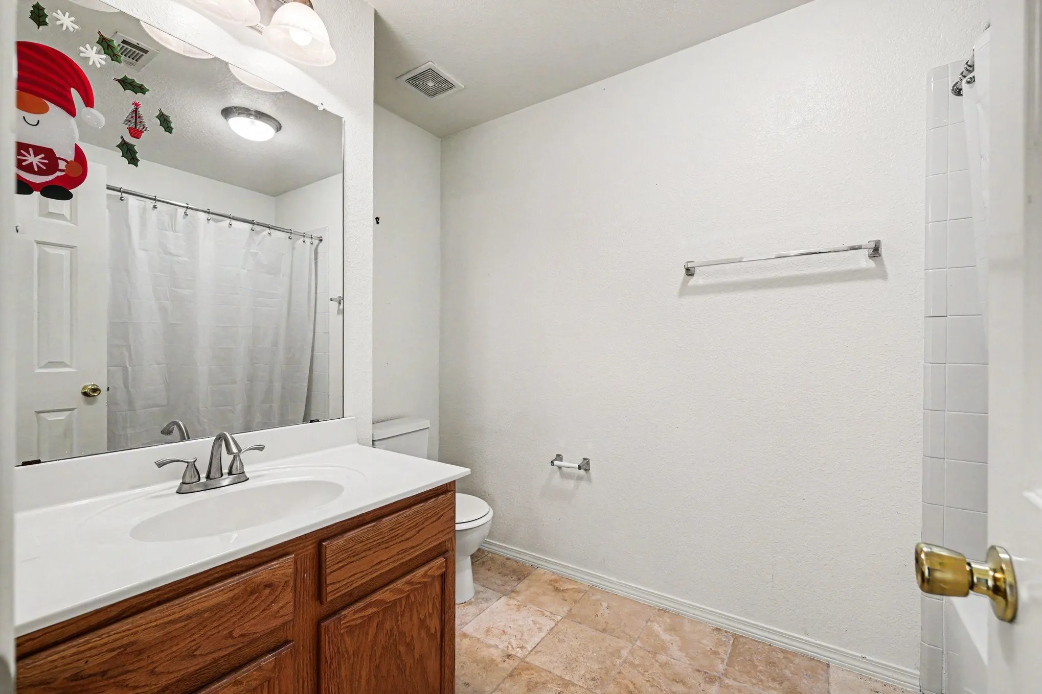 Bathroom featuring a wood-finish vanity with an integrated sink, polished chrome faucet, and a wall-mounted mirror
