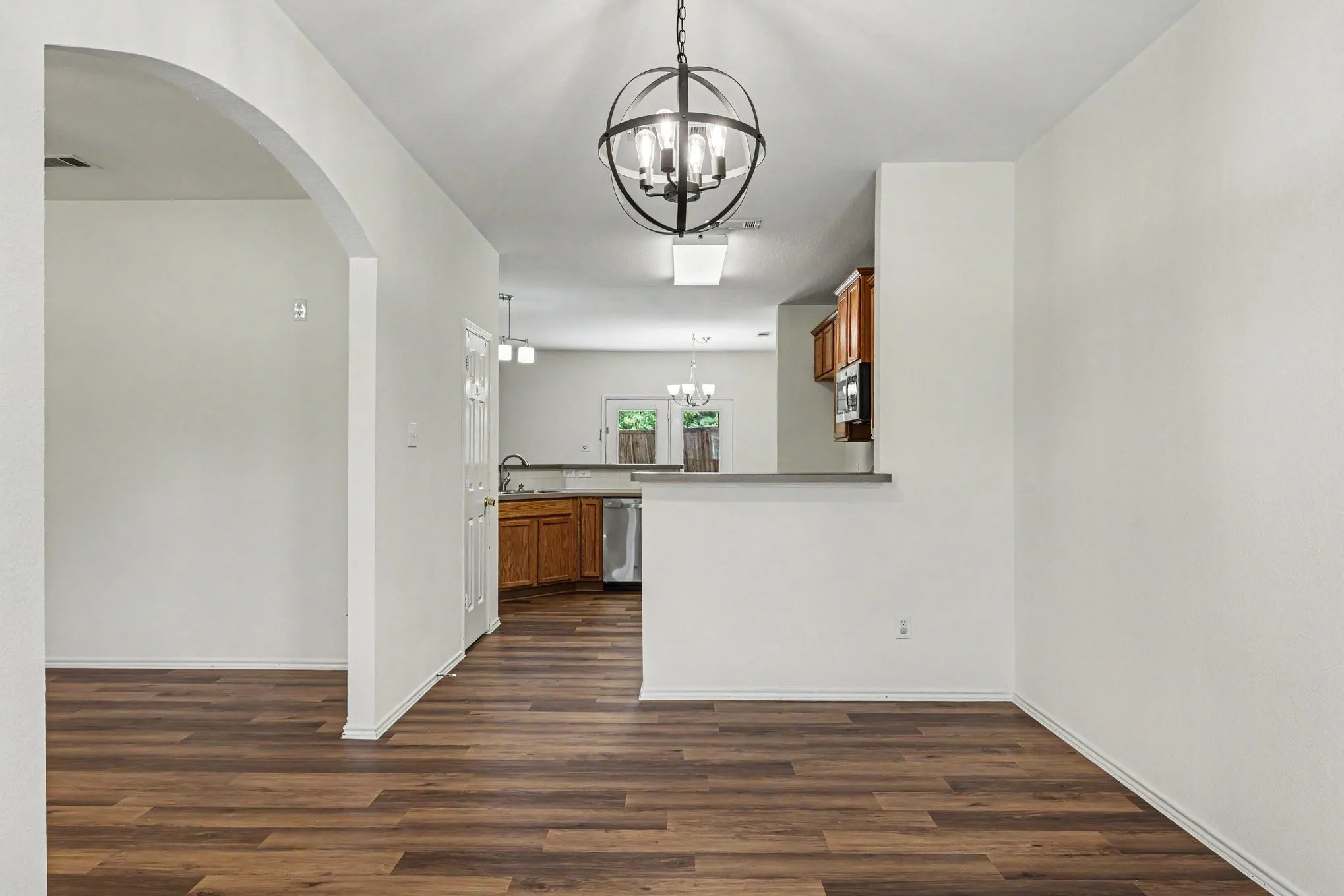 Wood-finish flooring throughout, complemented by an arched doorway and a contemporary hanging light fixture