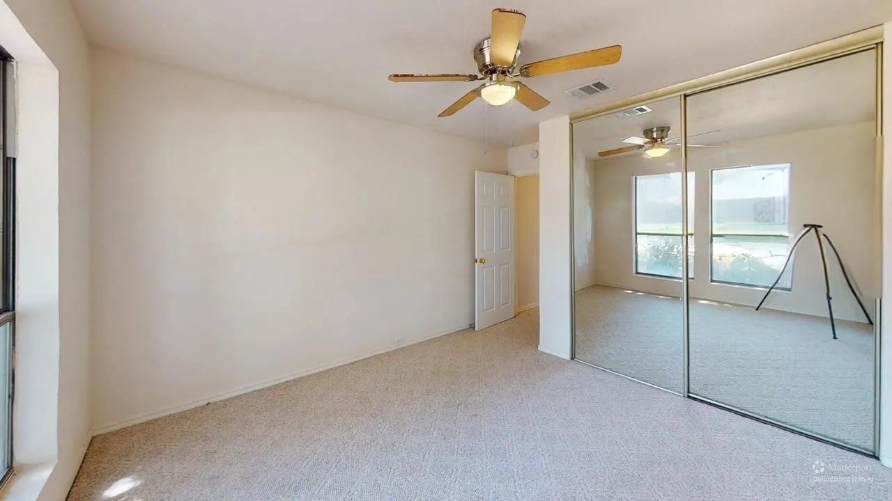 Wall-to-wall carpeting, ceiling fan with integrated lighting, mirrored sliding wardrobe doors, paneled interior door, and large window