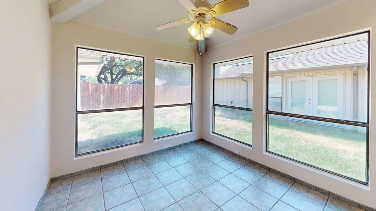 Tile flooring, multiple windows, exposed beam ceiling, and a ceiling fan with integrated lighting