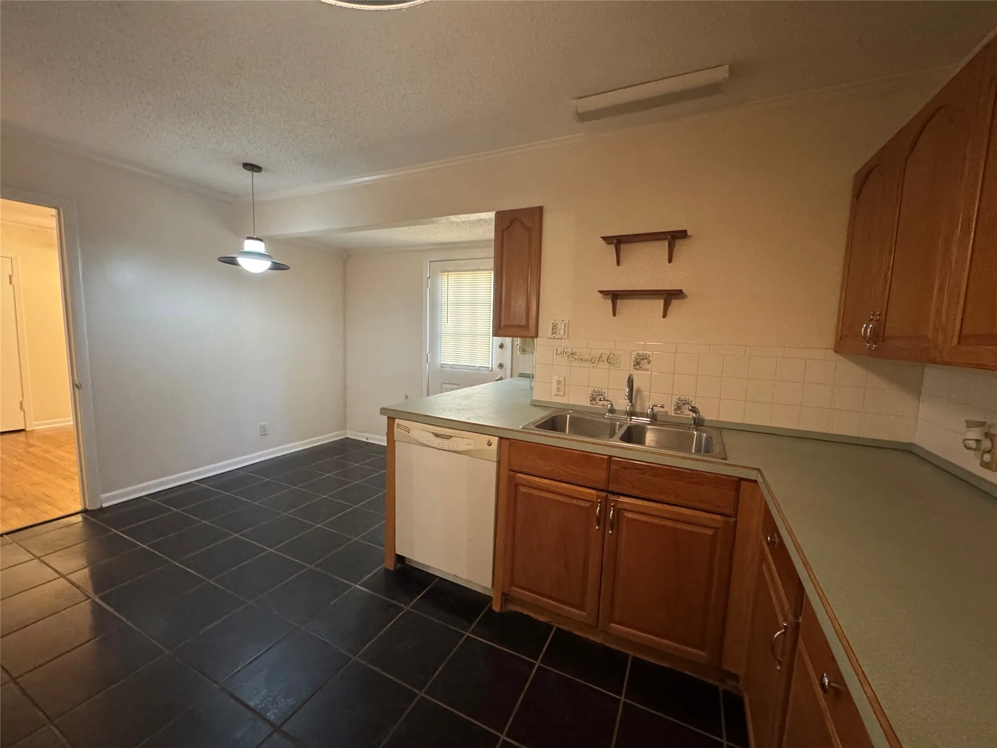 Kitchen featuring tile flooring, wood cabinetry, tile backsplash, a double basin sink, and a dishwasher