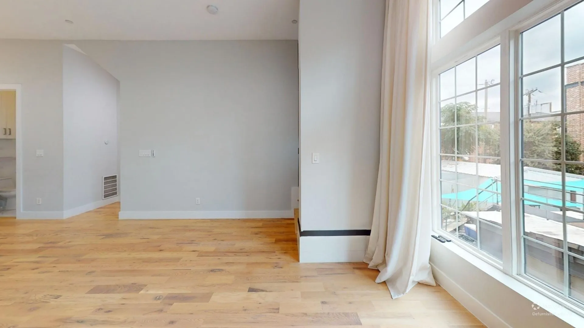 Hardwood flooring, high ceilings, large multi-pane windows, white baseboards, and light-toned walls