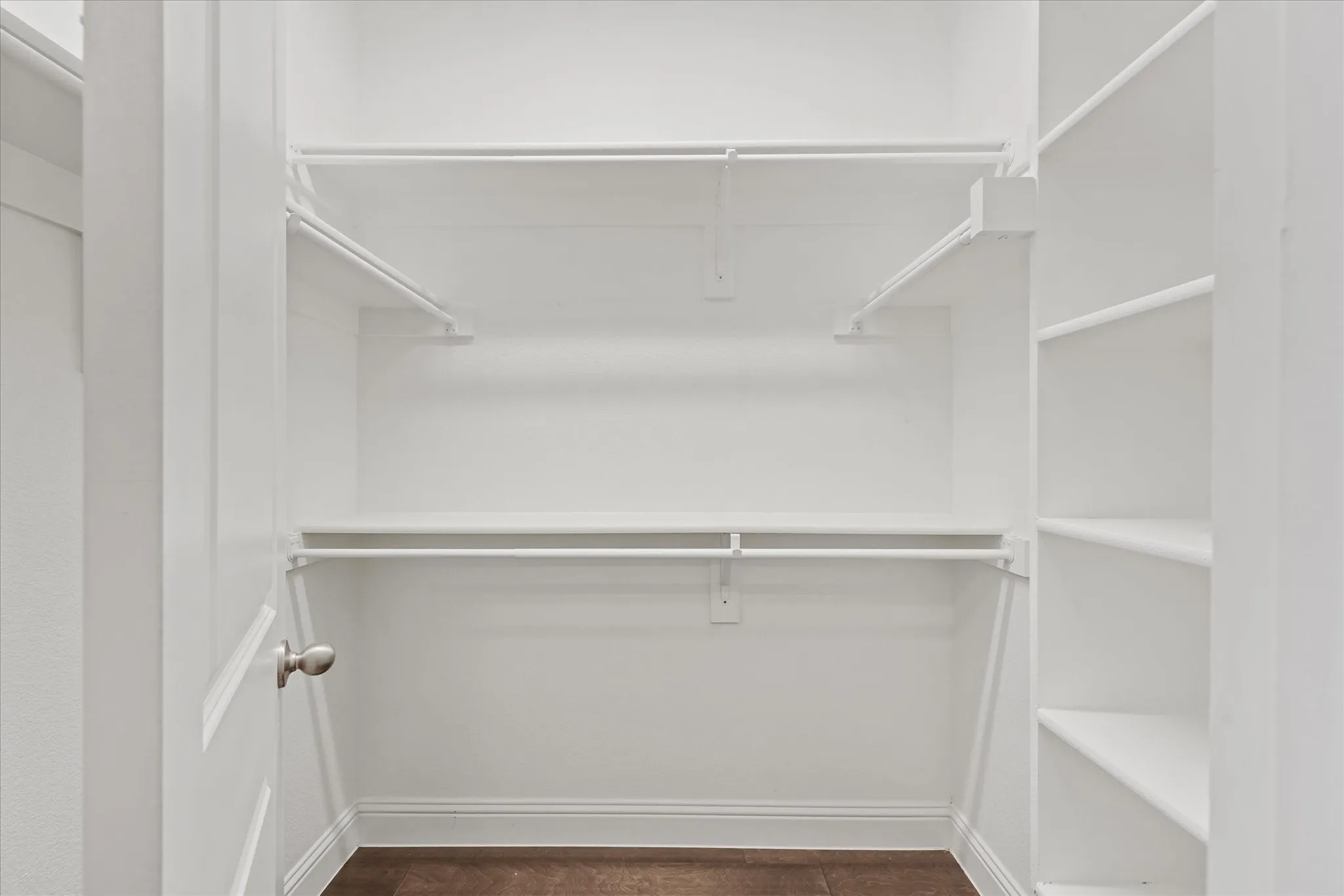 Walk-in closet featuring built-in shelving, multiple hanging rods, and wood-finish flooring