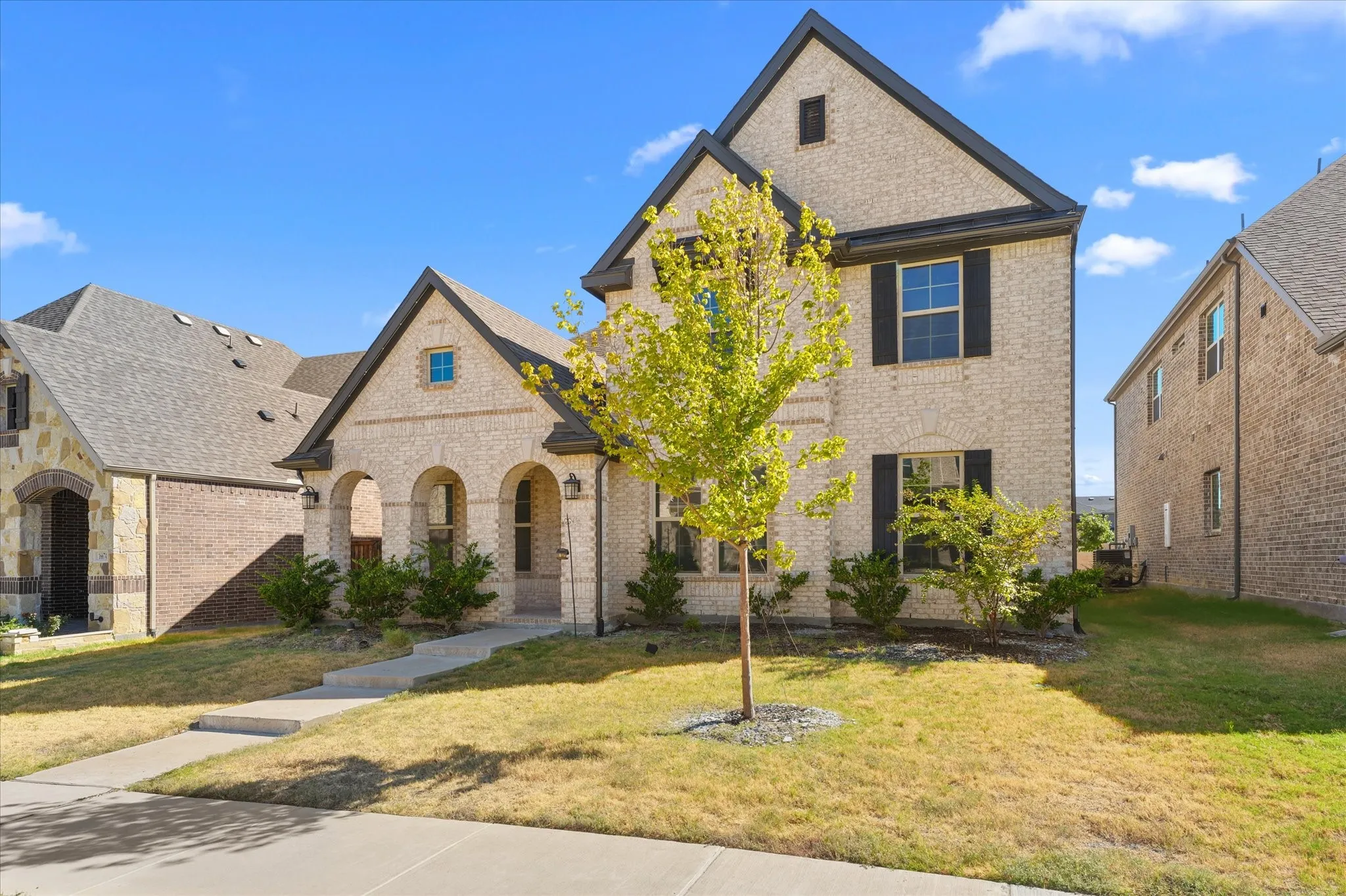 Brick exterior with arched entry, dark trim, and shutters