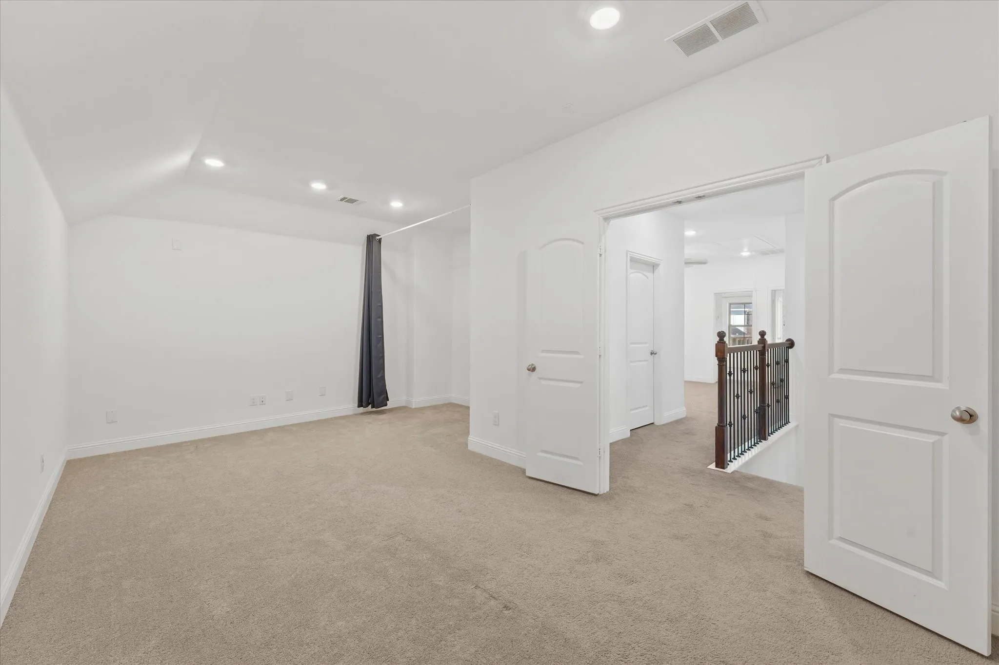 Carpeted room with recessed lighting, vaulted ceiling, and white paneled doors with arched tops
