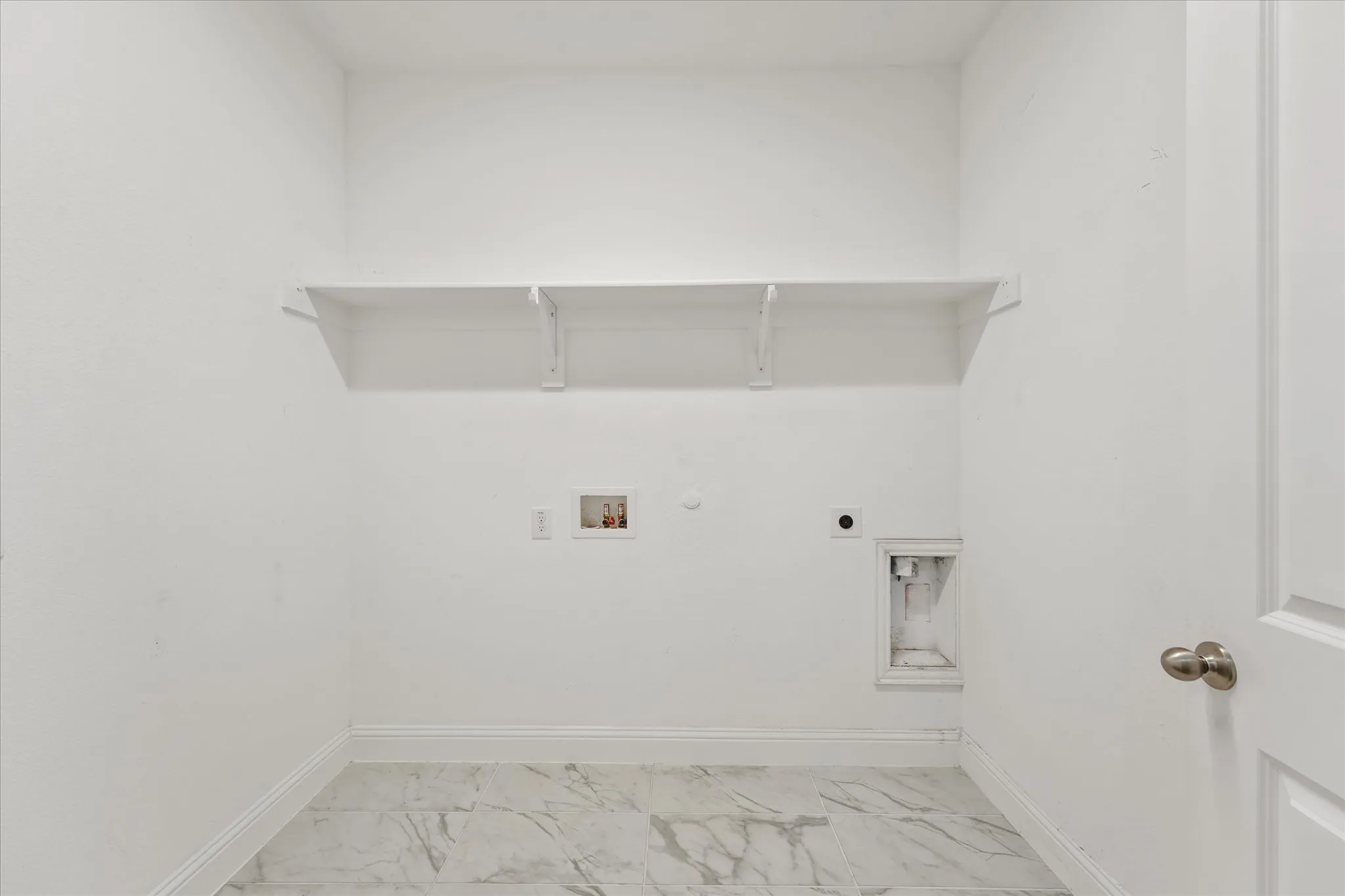 Laundry area with a built-in shelf, plumbing hookups, electrical outlet, and tile flooring