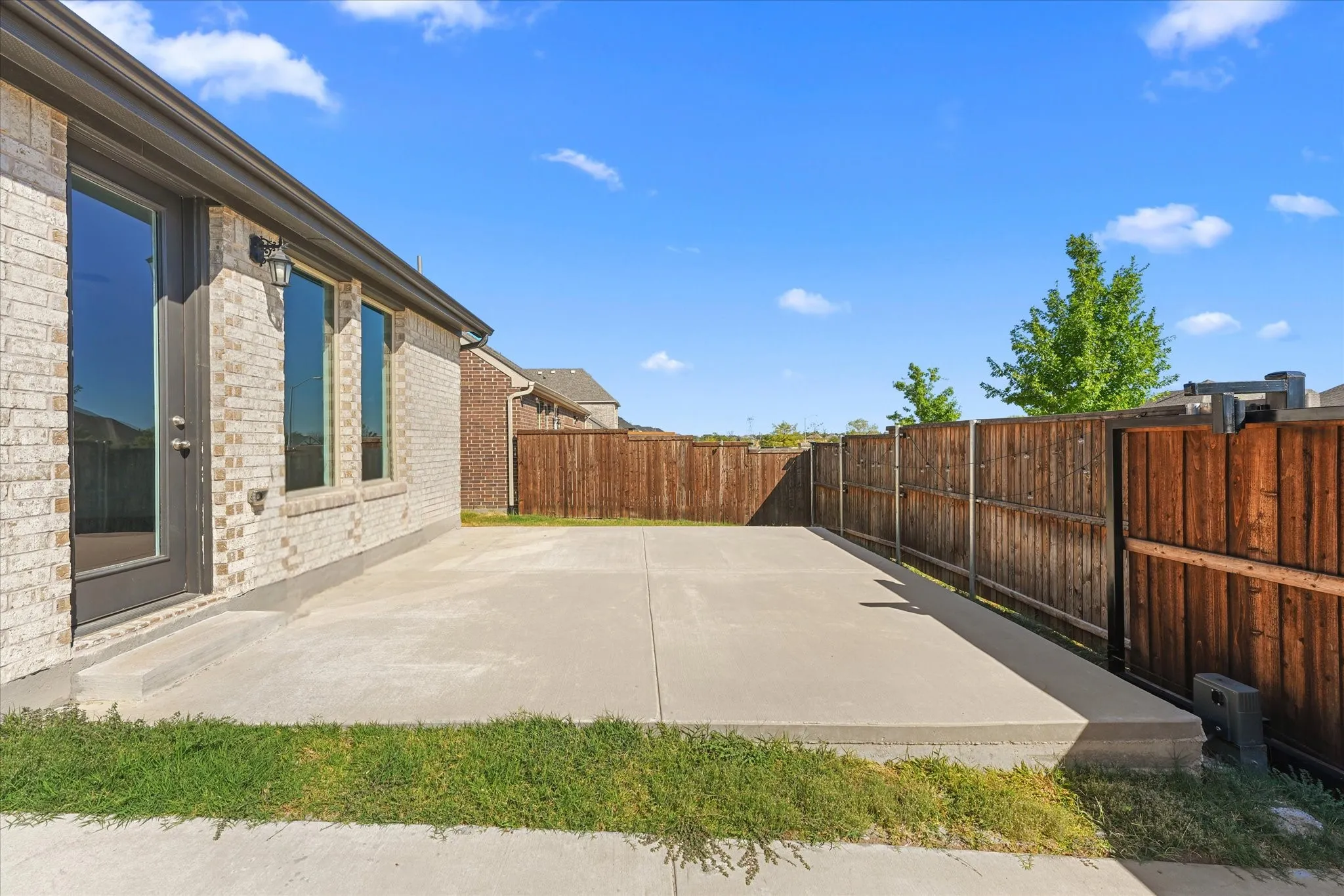 Expansive concrete patio with brick exterior and dark-framed windows