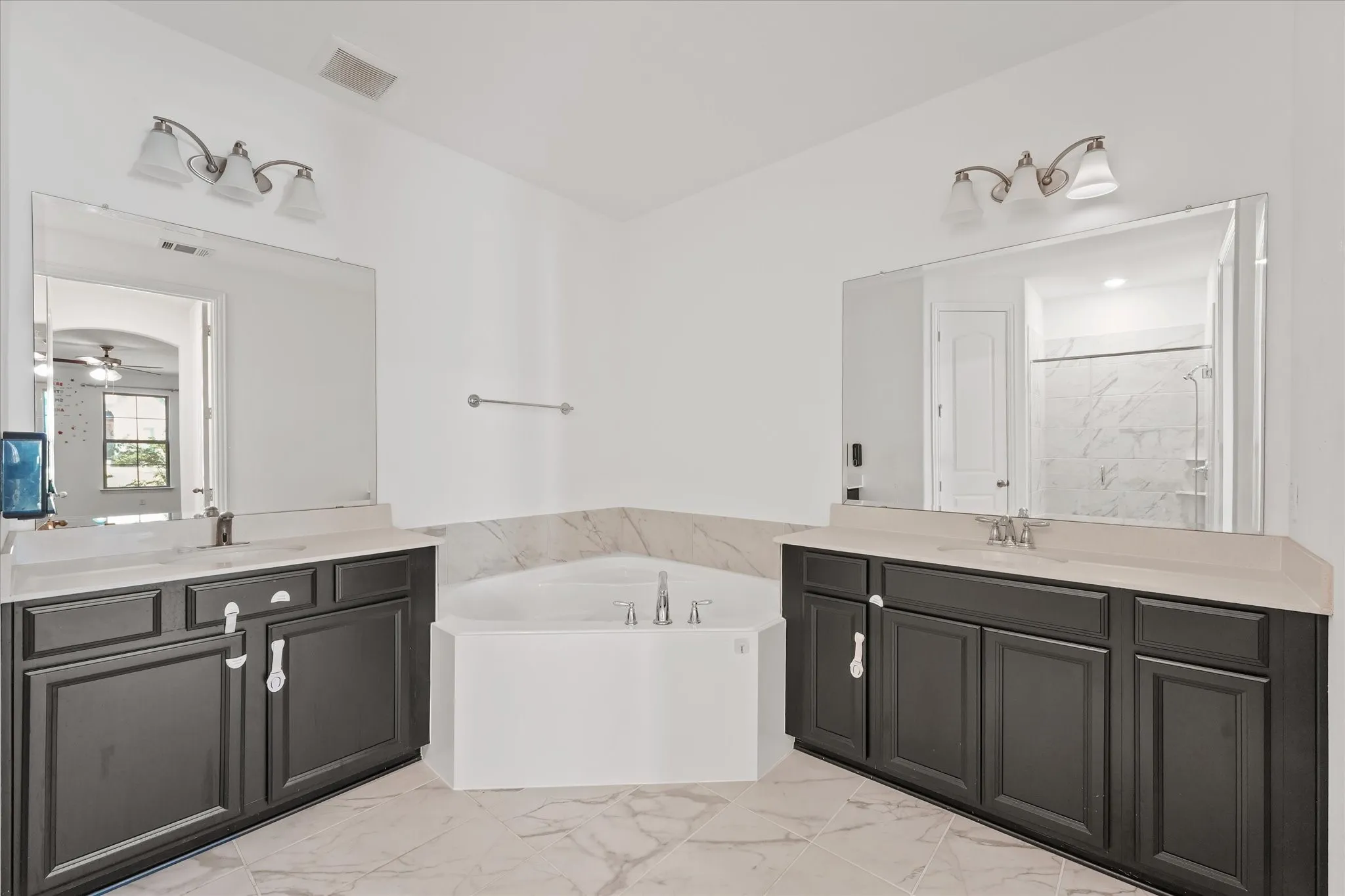 Dual vanities with dark cabinetry, light countertops, and individual mirrors