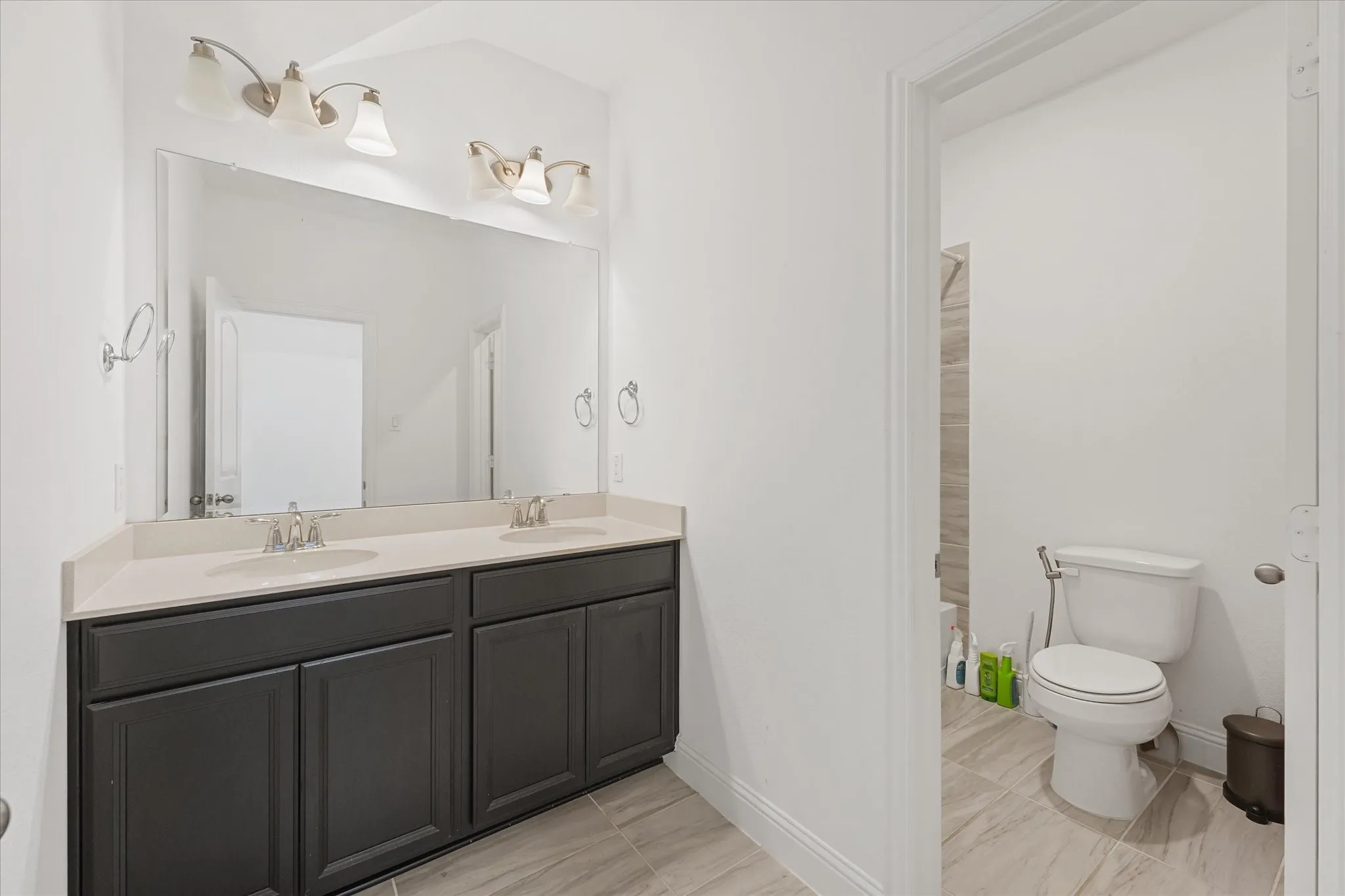 Dual vanity featuring a light countertop, dark wood-finish cabinetry, and brushed nickel fixtures