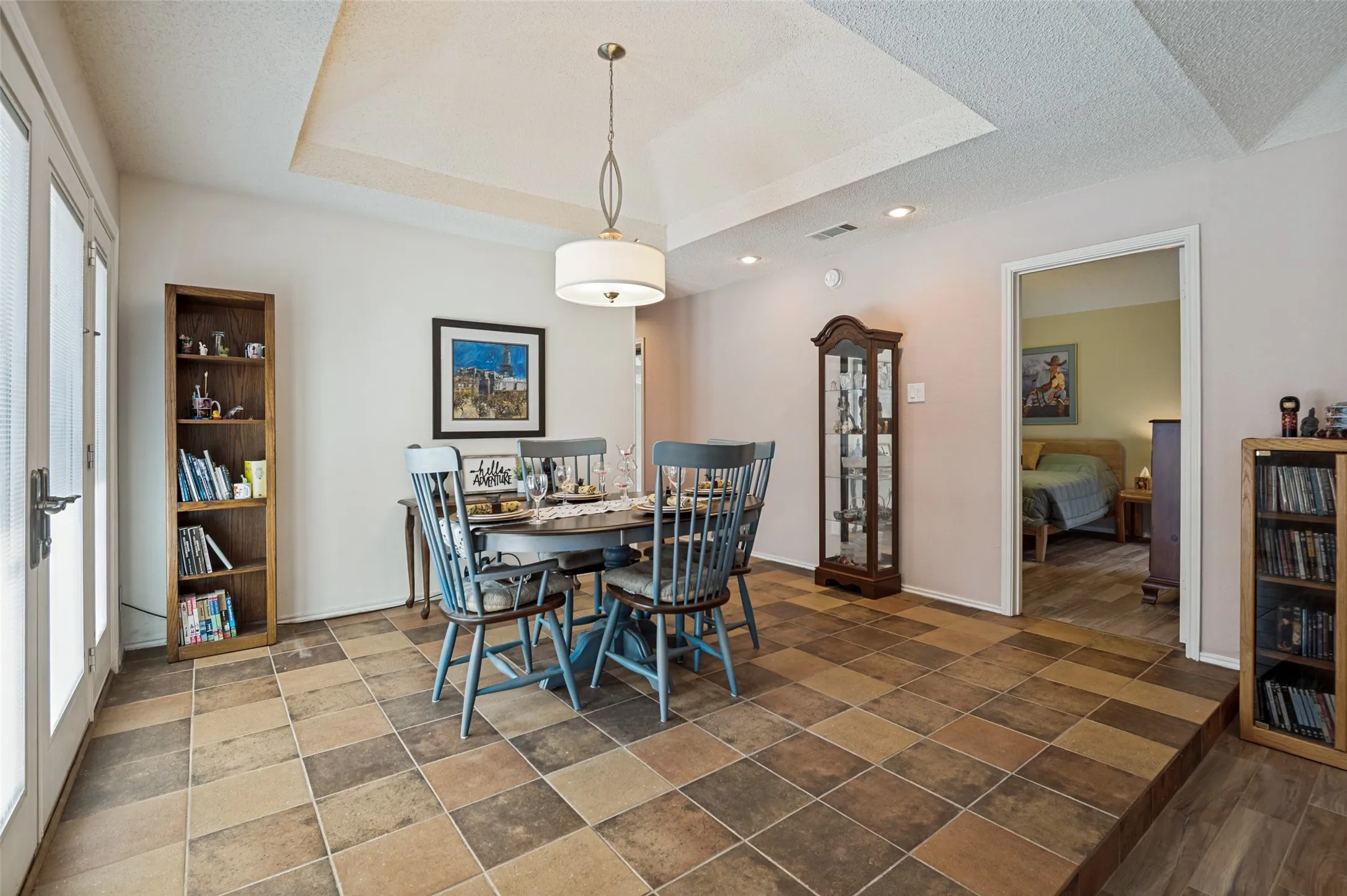 Dining area with multi-tone tile flooring, tray ceiling, recessed lighting, and a drum pendant light fixture