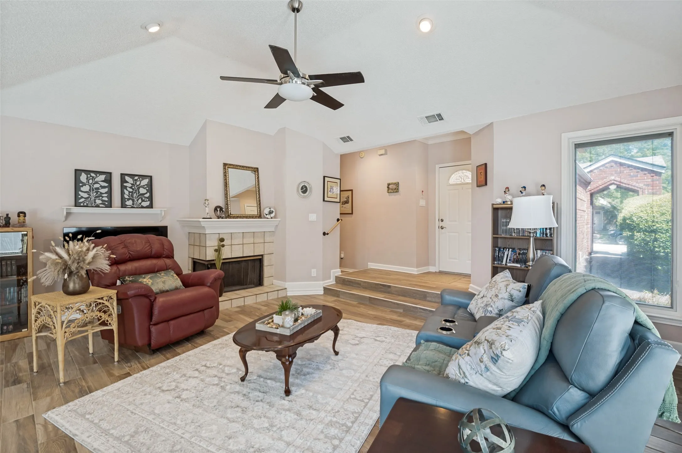 Vaulted ceiling with recessed lighting and ceiling fan, wood-finish flooring, and a tiled fireplace