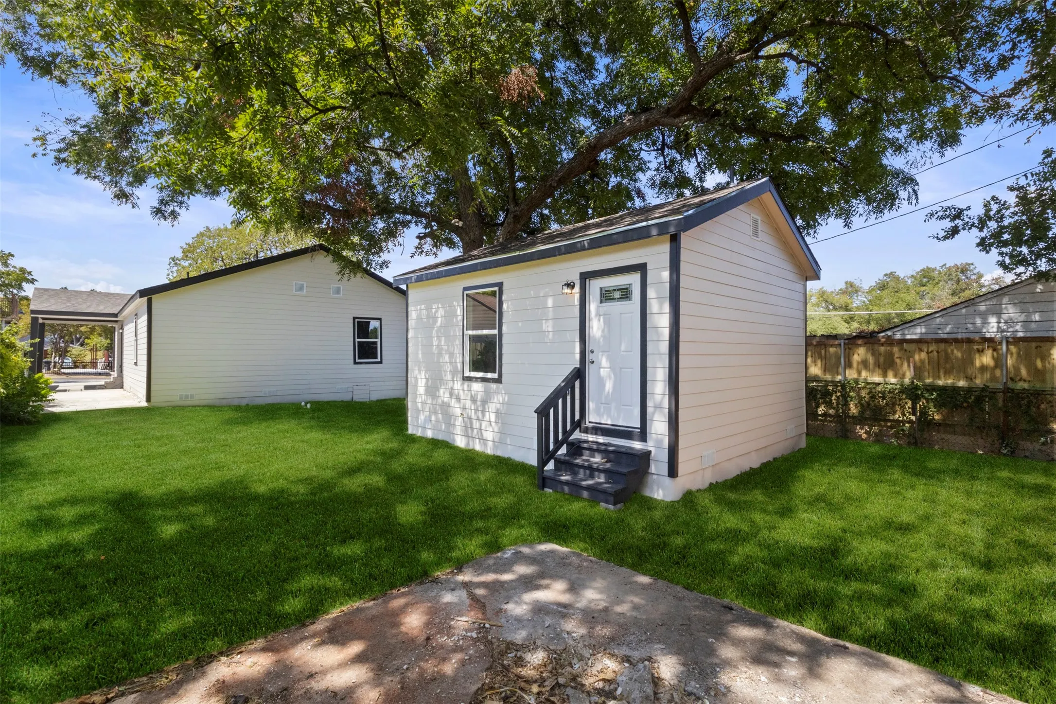 Detached structure with white siding, dark trim, and a private entrance