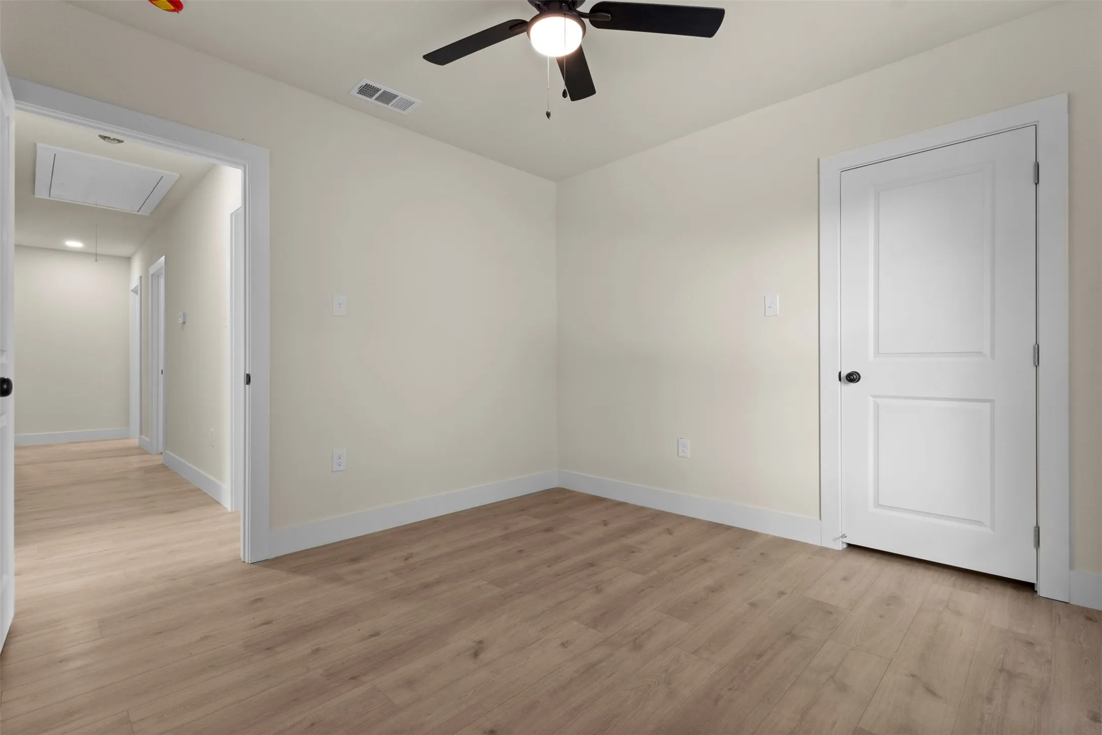 Wood-finish flooring, neutral wall tones, contrasting white trim, and a ceiling fan with integrated lighting