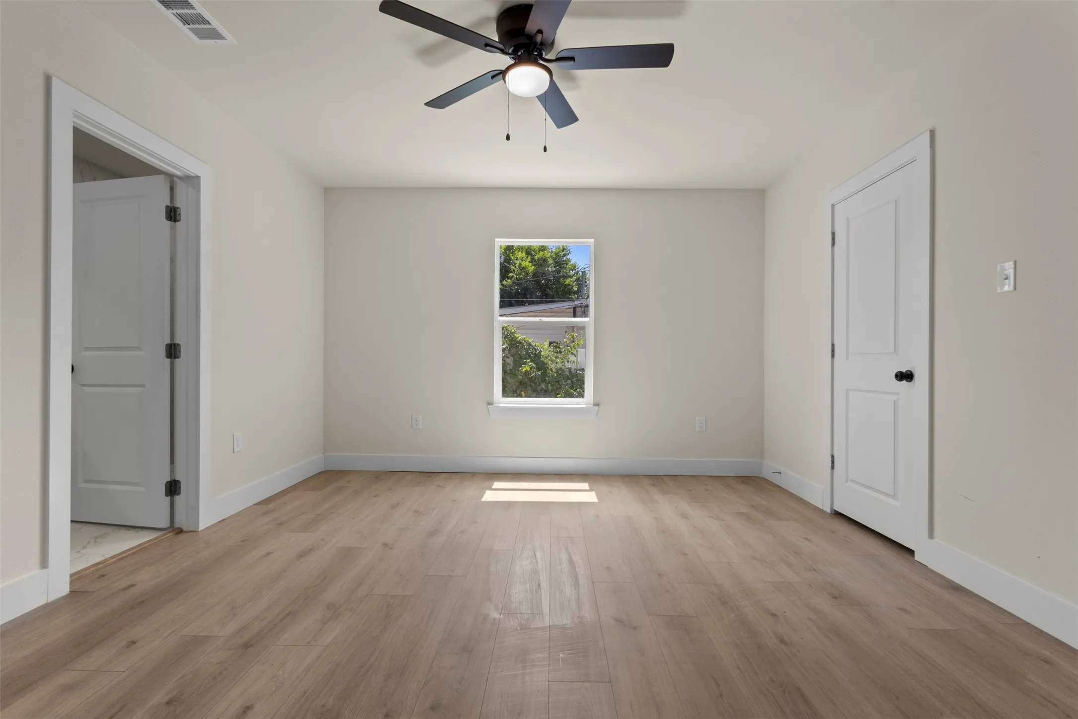 Wood-finish flooring, crisp white trim, and a ceiling fan with integrated lighting