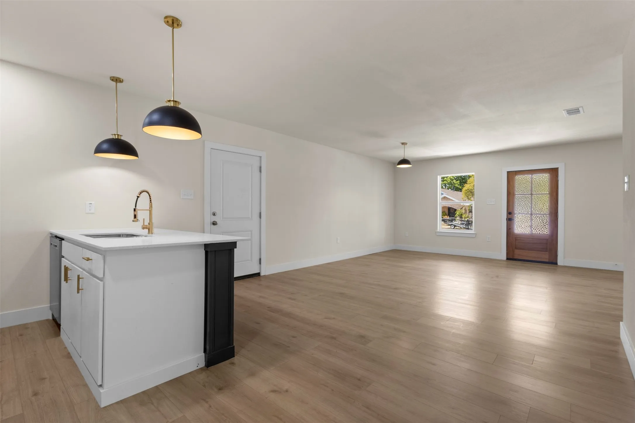 Kitchen island with white cabinetry, gold-tone hardware, and an undermount sink