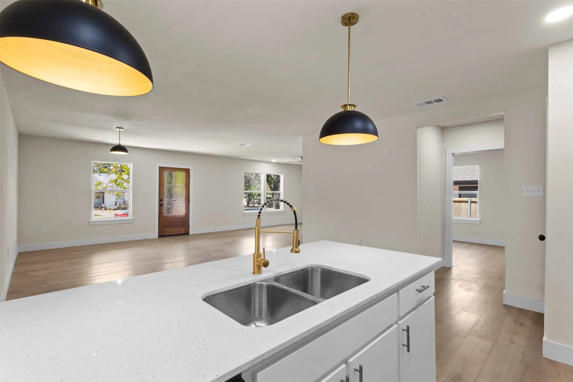Kitchen island with a double basin stainless steel sink, gold-finish faucet, and white quartz countertop