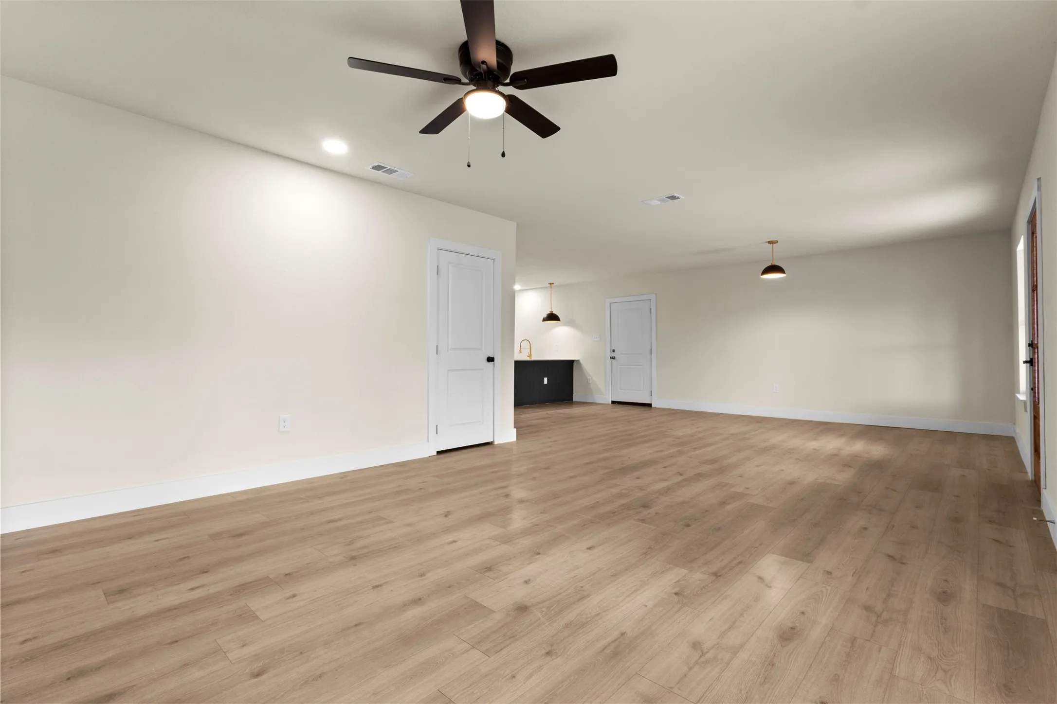 Spacious room featuring wood-finish flooring, recessed lighting, ceiling fan, and pendant lighting