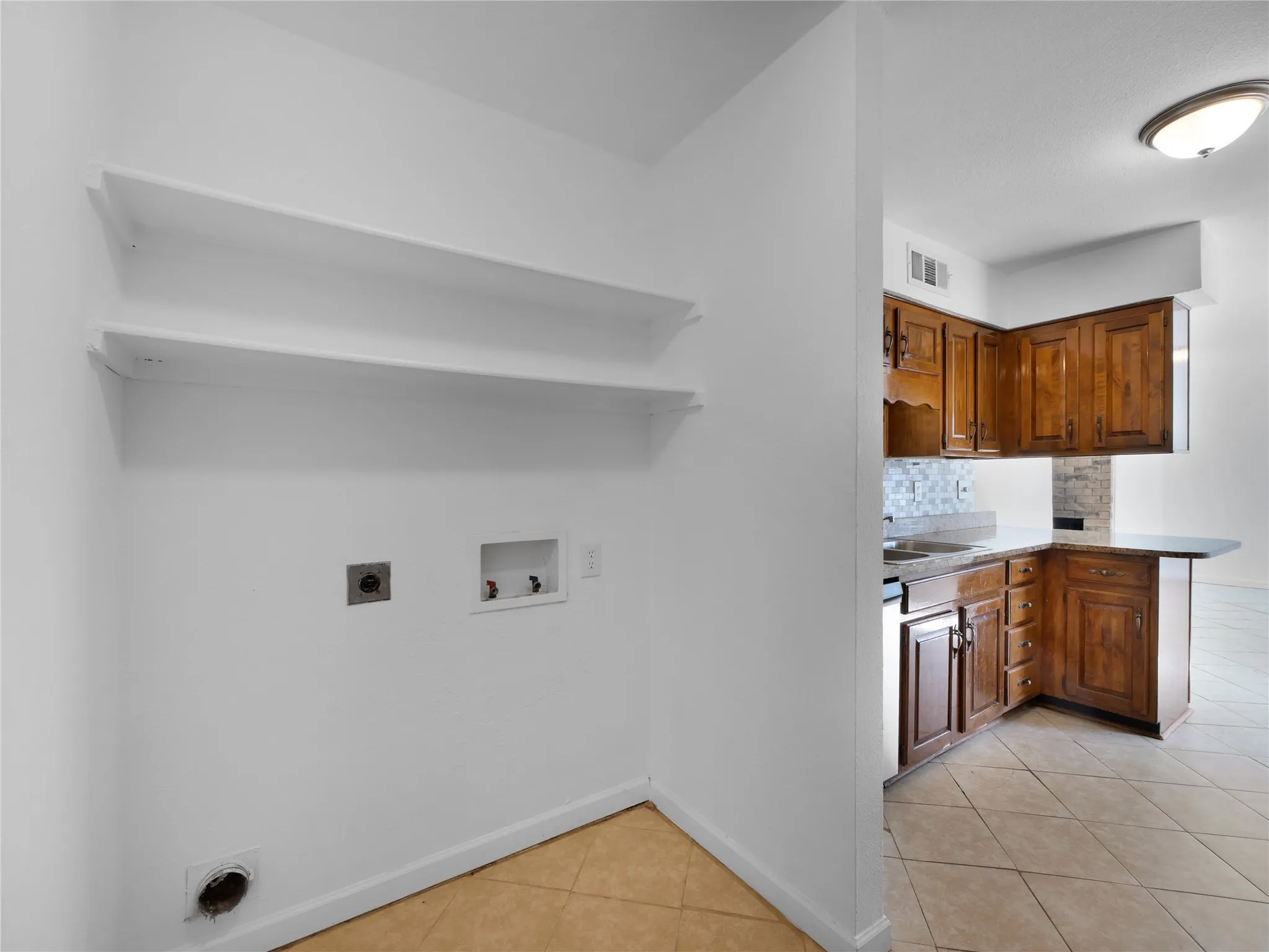 Laundry area with built-in shelving and tile flooring