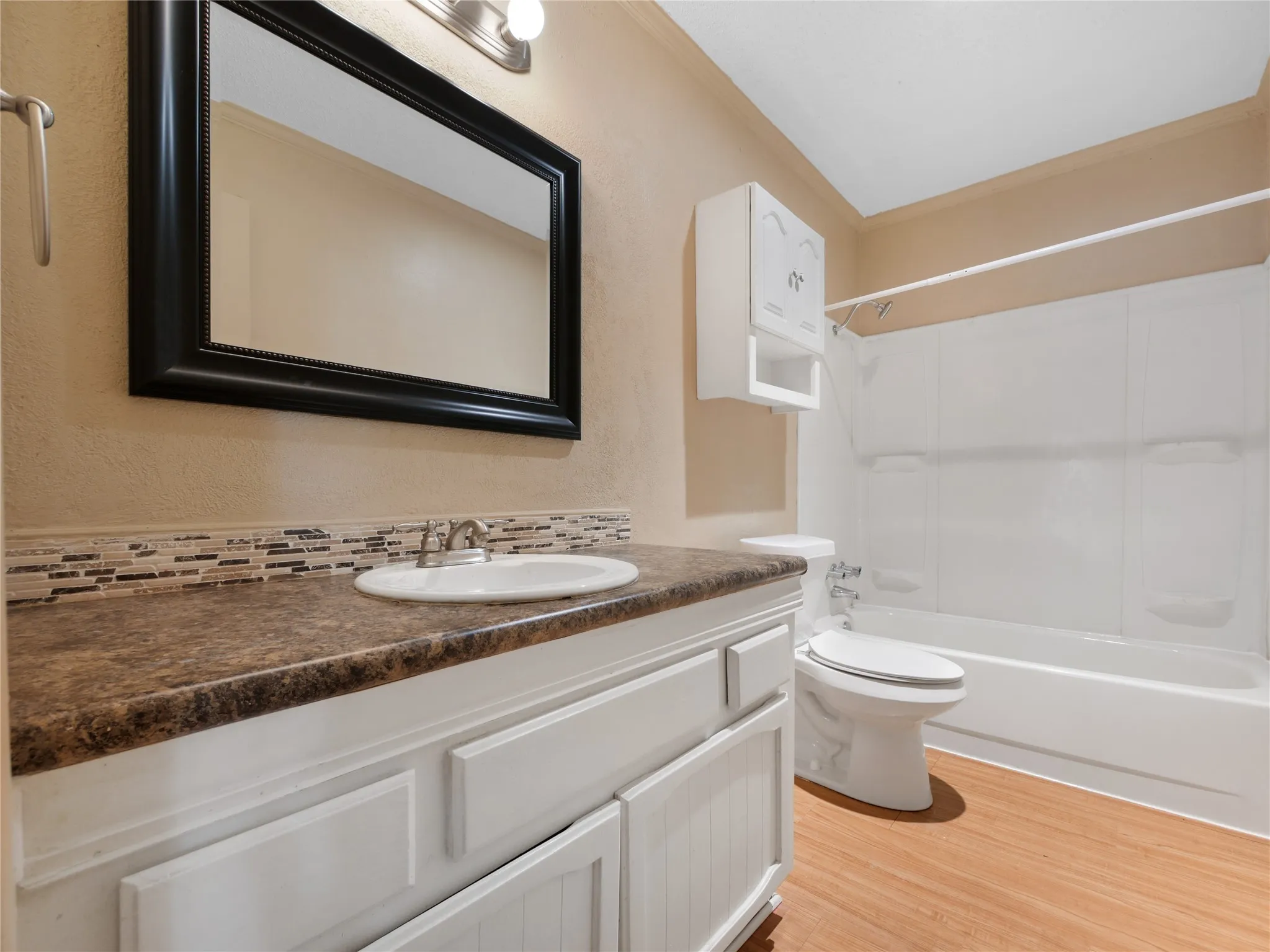 White vanity with beadboard paneling, laminate countertop, and mosaic tile backsplash