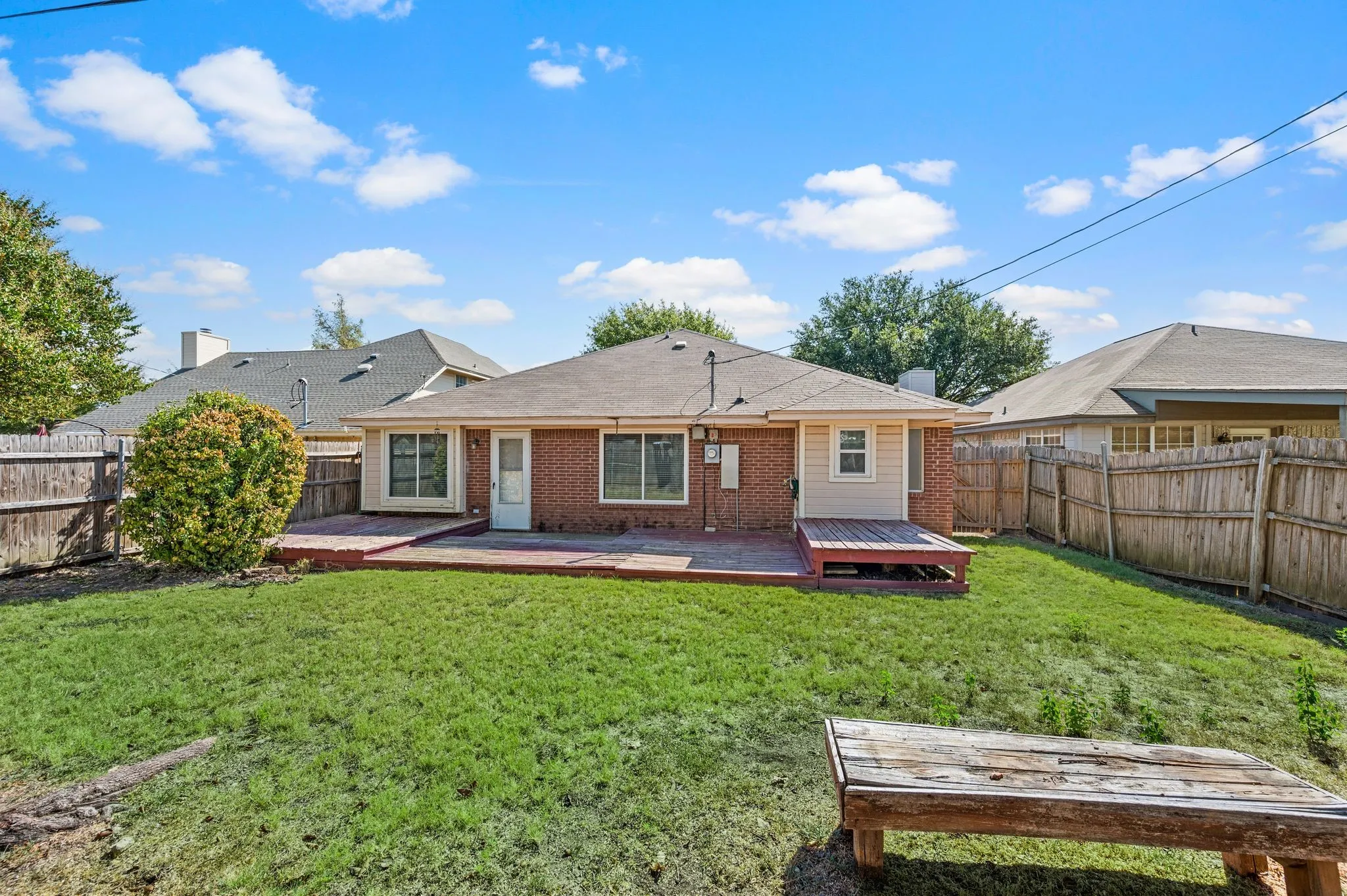 Wide rear view highlights the home’s expansive deck & generous fenced yard.