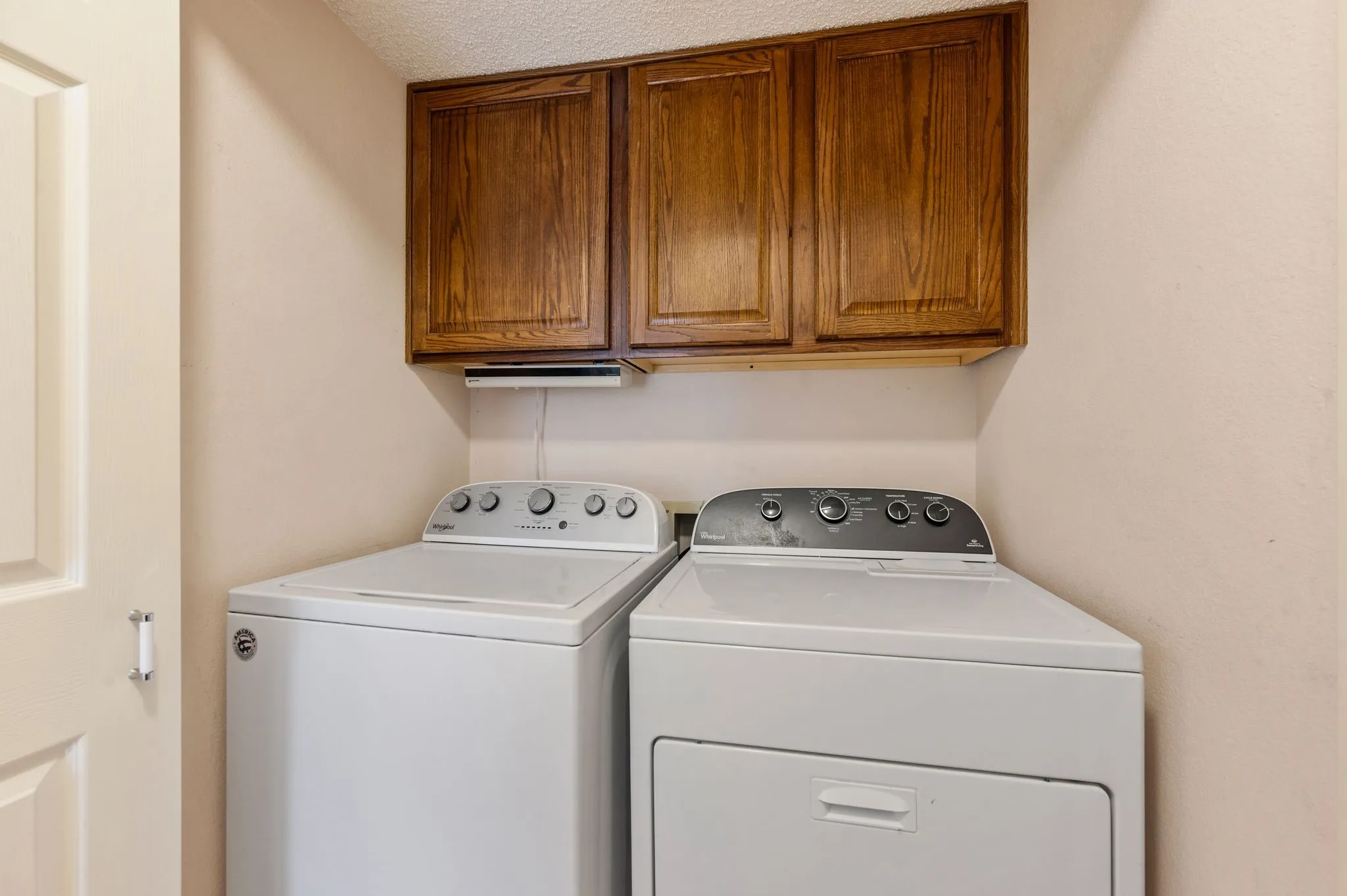 Dedicated laundry area includes convenient upper cabinetry for added storage.