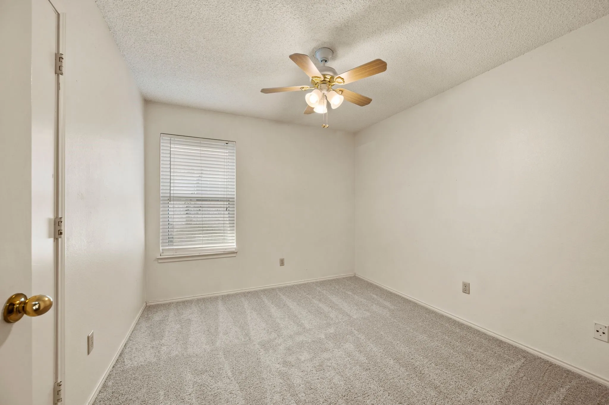Comfortable secondary bedroom features new carpet, a ceiling fan & natural light.