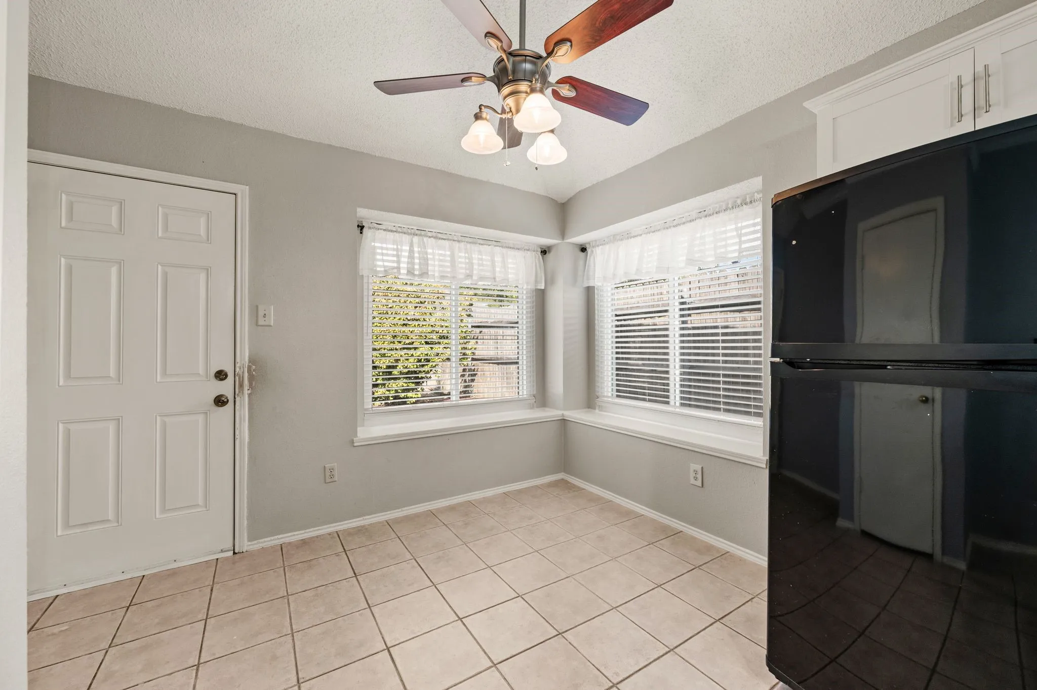Sunny breakfast nook features wraparound windows, tile flooring & backyard access.