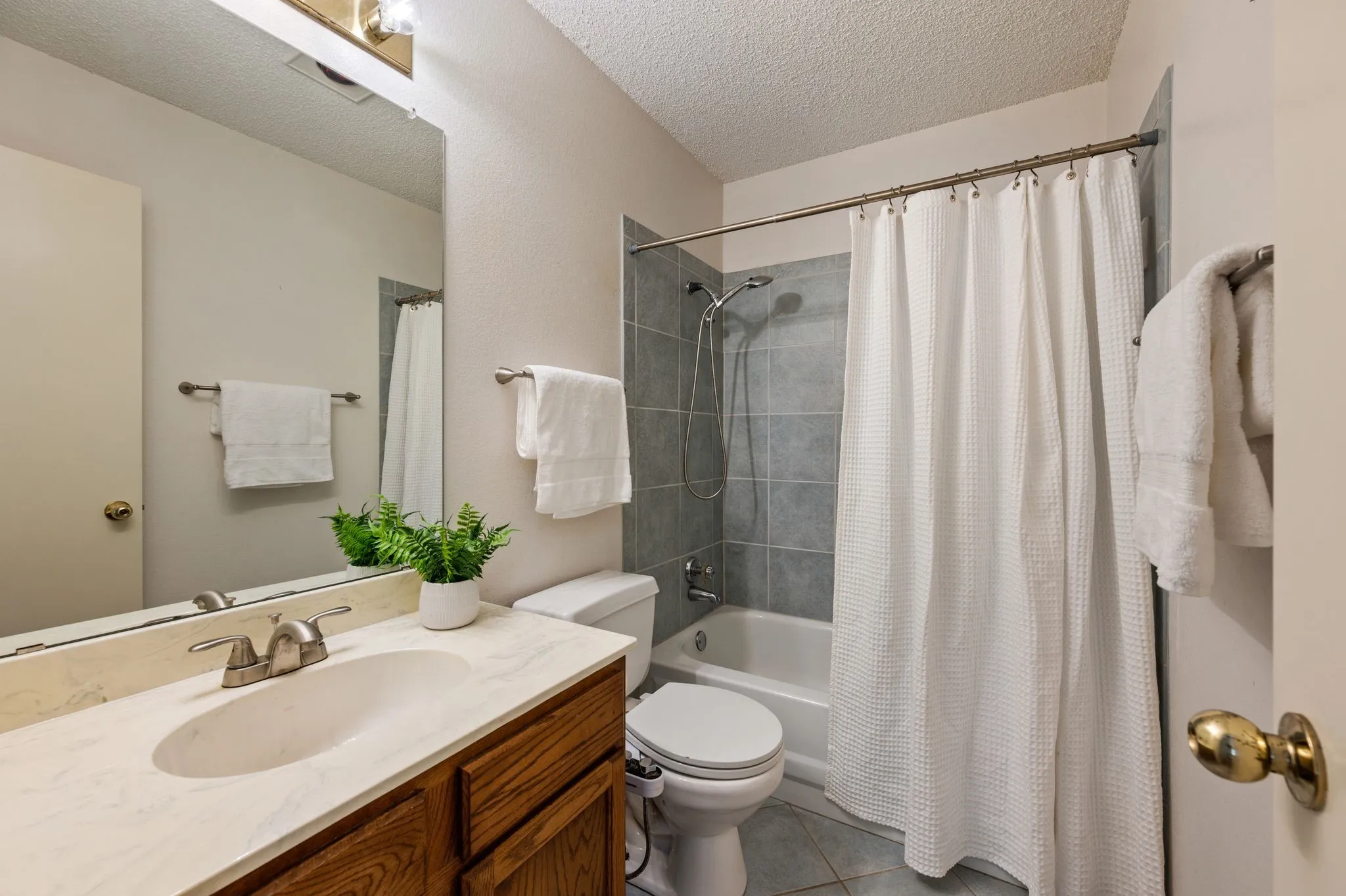 Secondary bath offers a tub-shower combination with tile surround, generous counter space & a large mirror.