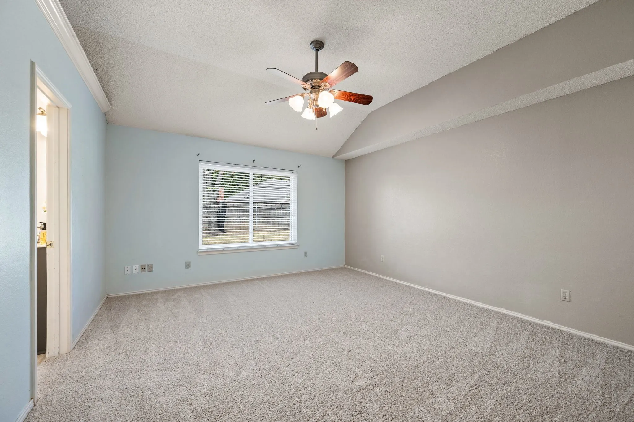 Spacious primary bedroom features a vaulted ceiling, soft carpeting & an ensuite bath.